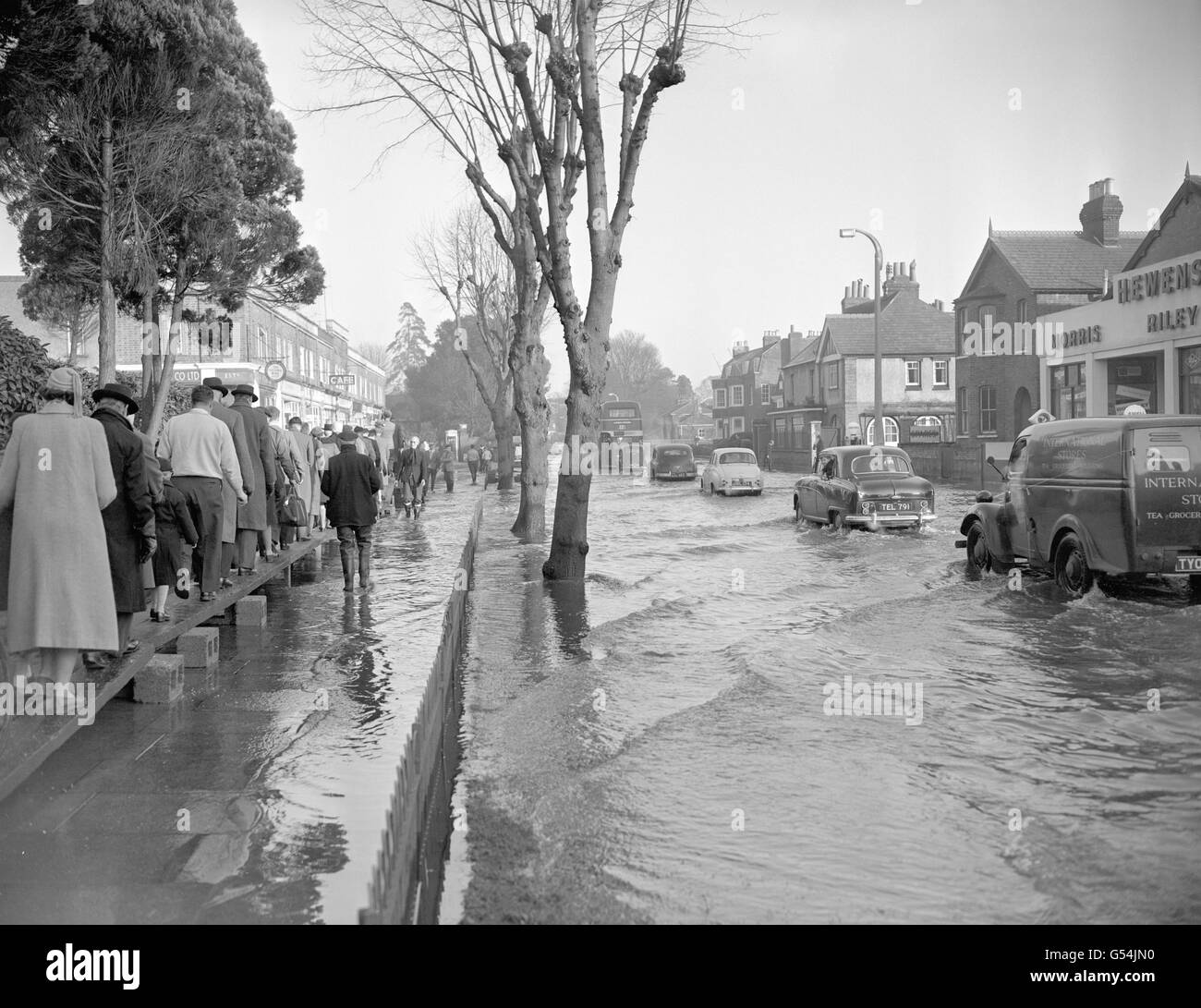 Gli automobilisti e i pedoni viaggiano attraverso le acque alluvionali in un unico file sulla principale Bath Road a Maidenhead, Berkshire, dopo che il Tamigi ha fatto esplodere le sue rive. Il fiume scoppiò a seguito di forti piogge nella zona. Foto Stock
