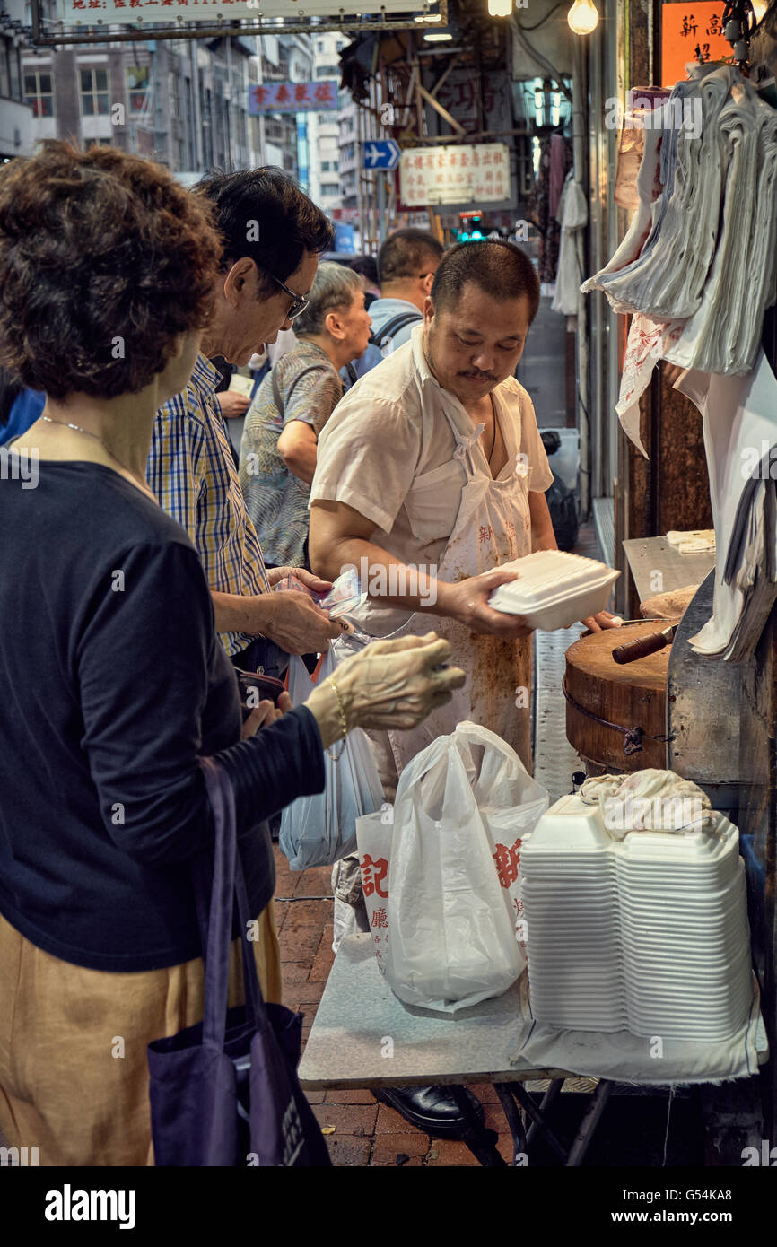 I clienti in coda e l'acquisto delle selezioni di portar via il cibo cotto in un negozio di Shanghai Street in Yau Ma Tei, Hong Kong. Foto Stock
