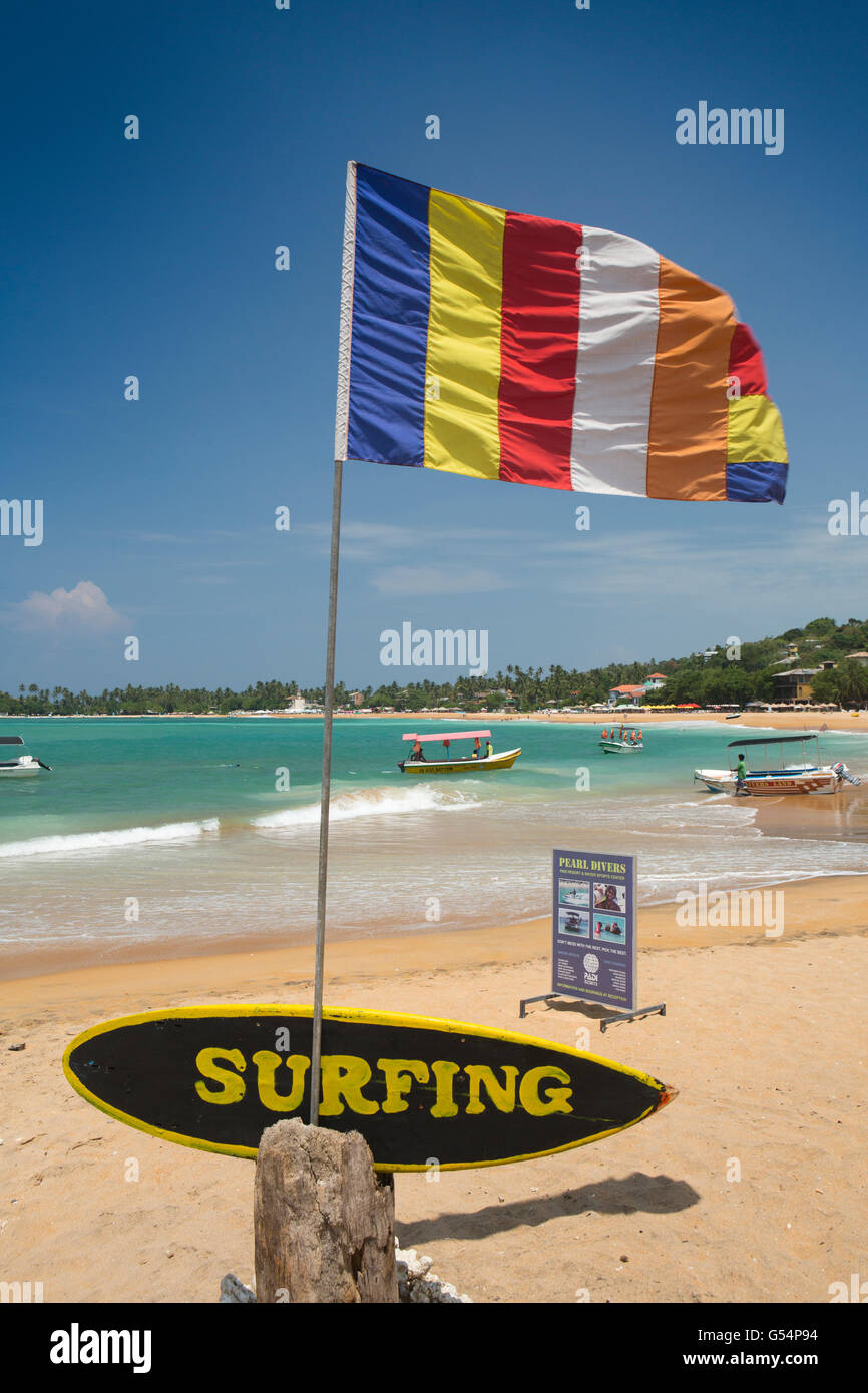 Sri Lanka Galle Provincia, Unawatuna beach, buddista battenti bandiera sopra segno di surf Foto Stock