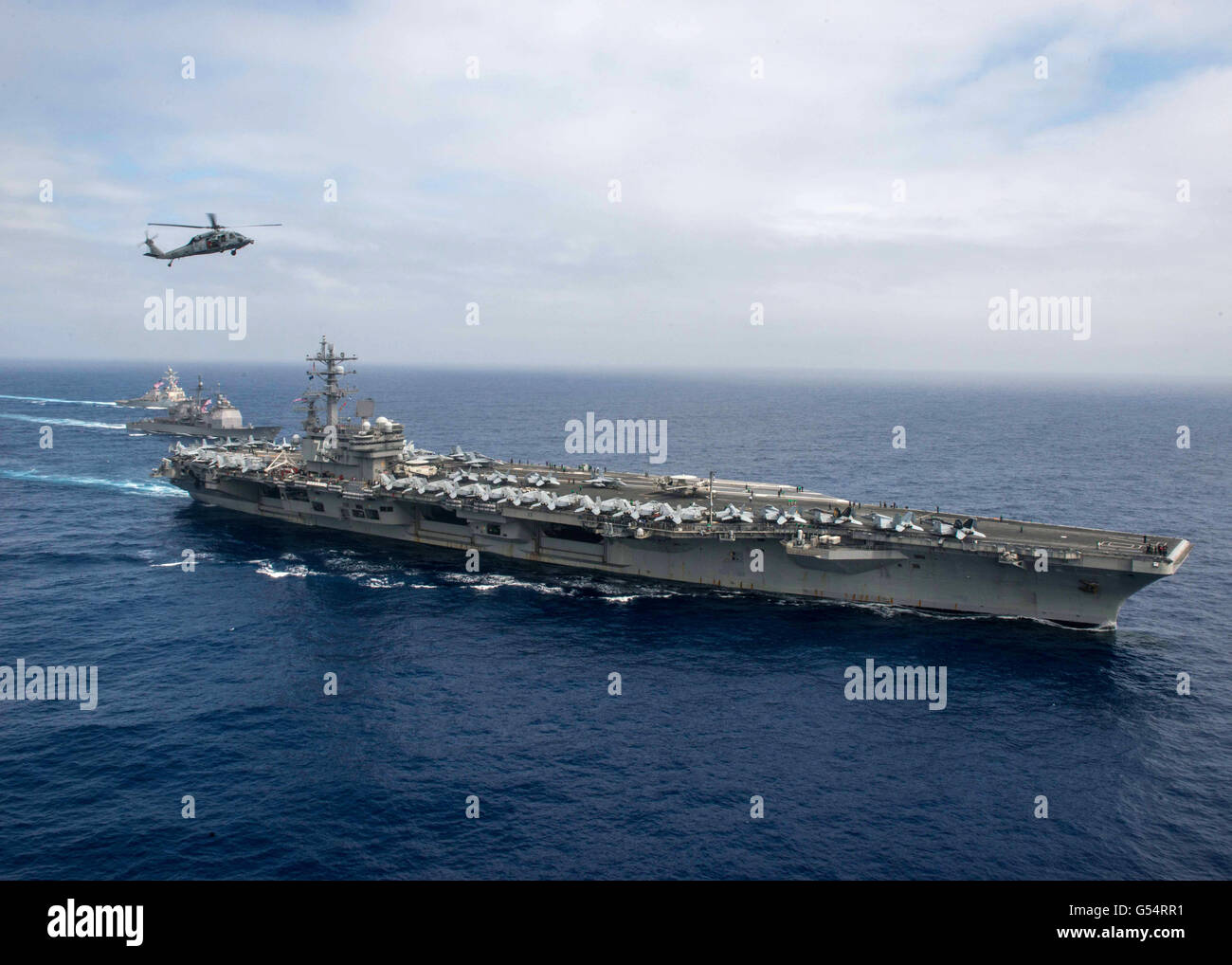 Un U.S Navy MH-60S Sea Hawk elicottero vola oltre la Nimitz-classe-nucleare powered super-carrier USS Ronald Reagan durante operazioni duali con la portaerei USS John C. Stennis Giugno 18, 2016 nel Mare delle Filippine. Foto Stock