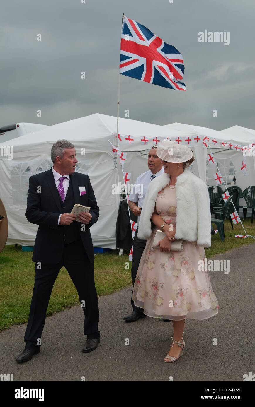 Sulla brughiera al Royal Ascot, una coppia elegantemente vestita e alla moda si gode una giornata di corse di cavalli. Bandiera Union Jack. Il lato Heath dell'ippodromo è molto più economico o gratuito. 2016 2010 HOMER SYKES Foto Stock