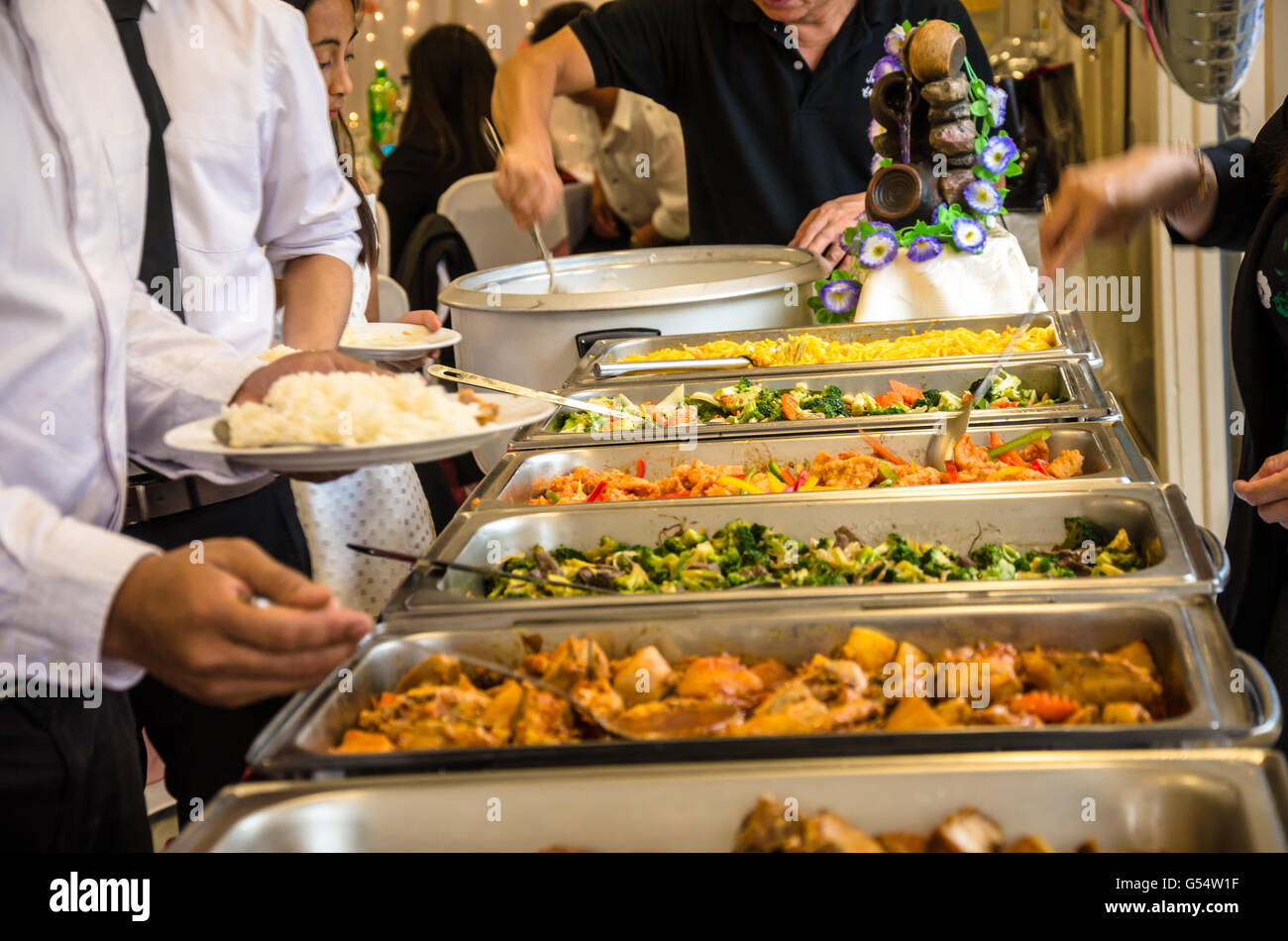 Le persone ad aiutare se stesse di cibo a buffet self-service a un party. Foto Stock