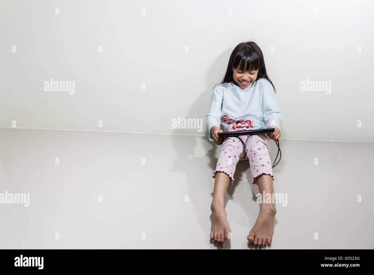 I bambini con il computer tablet Siediti sul pavimento - Tecnologia e concetto di bambini Foto Stock