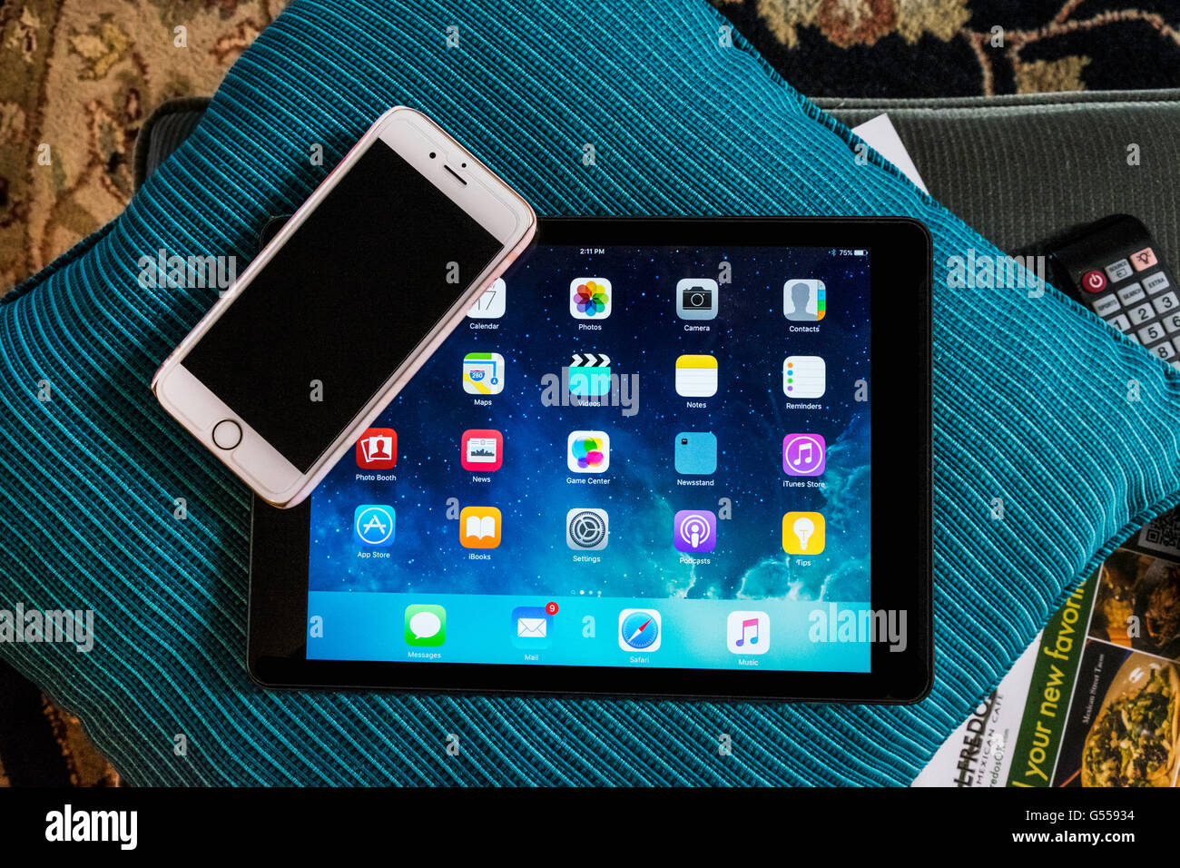 Un iPhone 6s giacente su un iPad aria che mostra la schermata di Start mentre giaceva su un cuscino per divani in un ambiente disordinato in ambienti chiusi. Stati Uniti d'America. Foto Stock