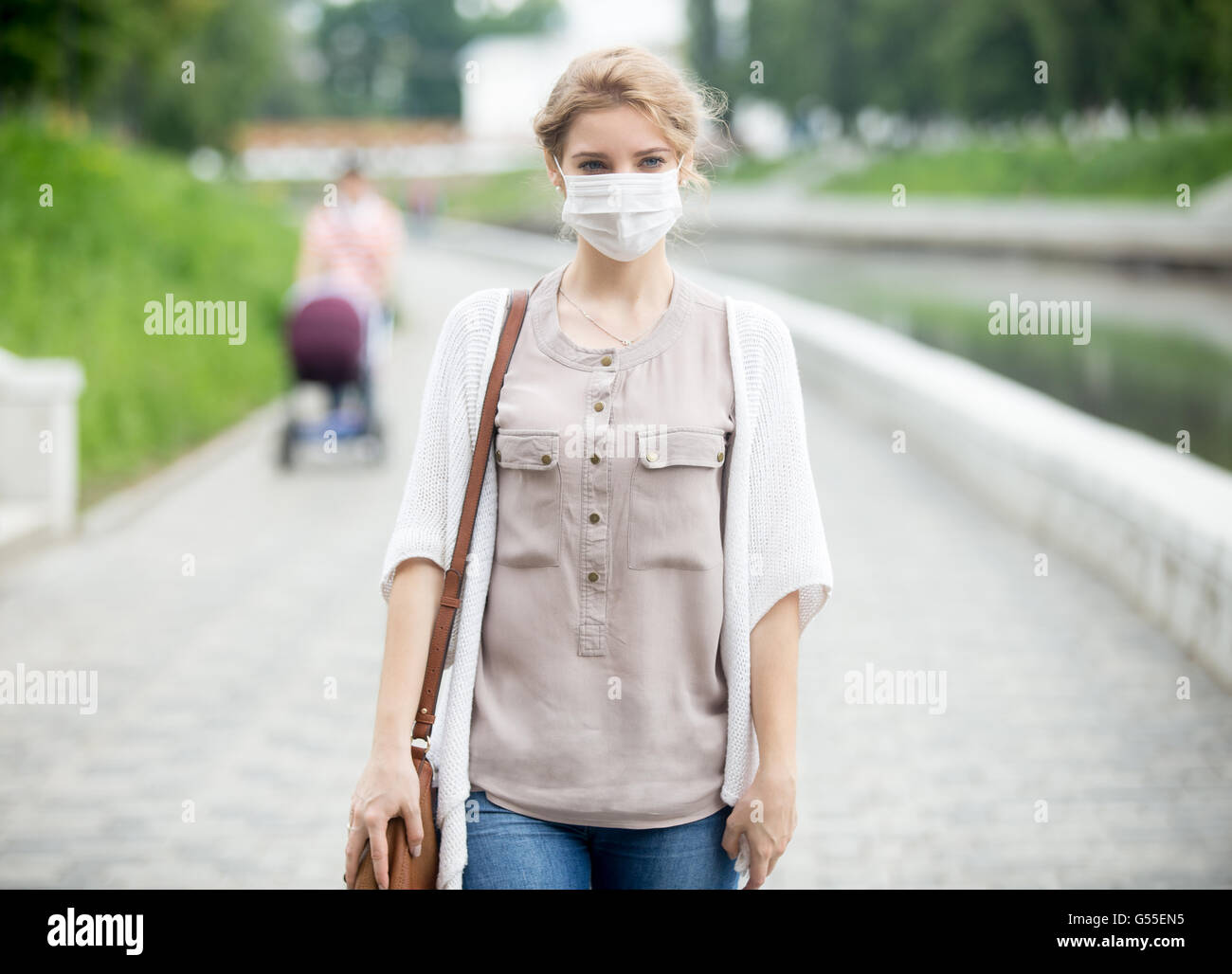 Ritratto di bella donna che cammina sulla strada di indossare la maschera protettiva come protezione contro le malattie infettive. Attraente Foto Stock