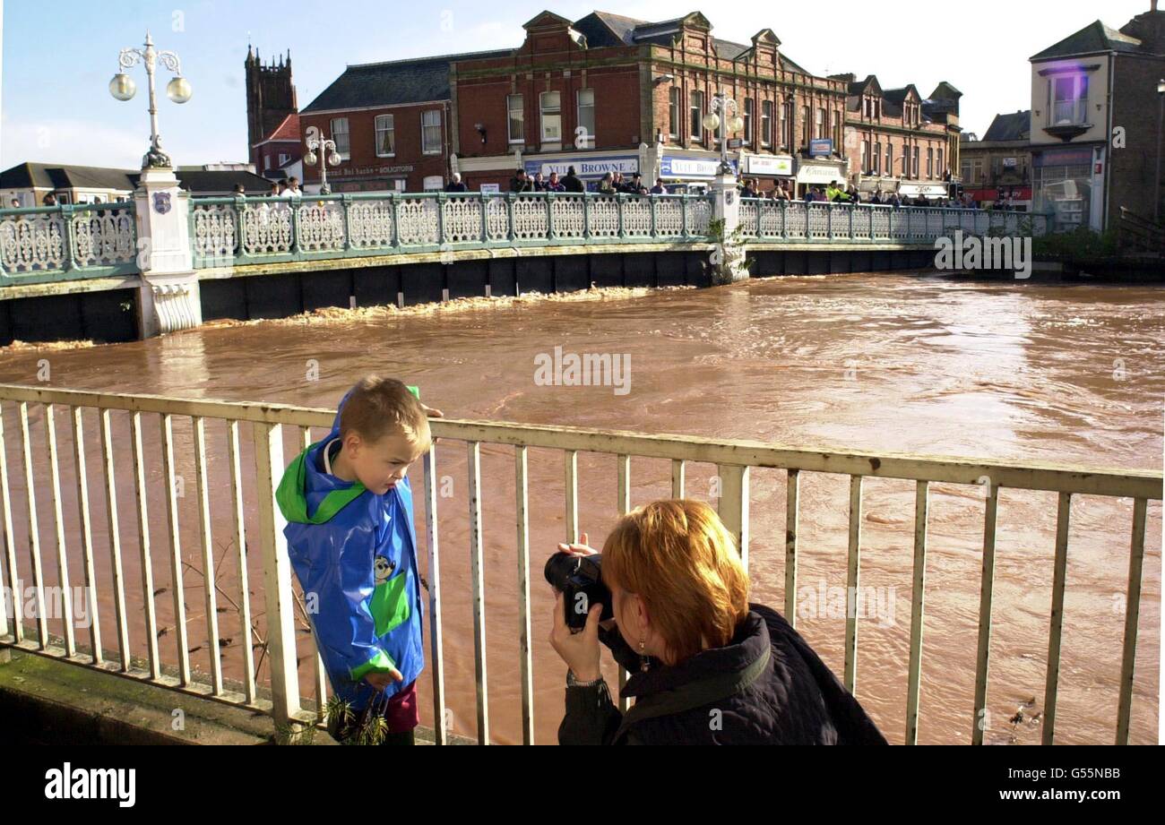 Melanie Mousseau scatta una foto del figlio Elias Arberry, 4 anni, mentre l'acqua alta nel tono del fiume scorre sotto il Ponte della Città a Taunton. Alcune parti della Gran Bretagna sono state schiacciate da una massiccia tempesta notturna che ha causato almeno due vittime, causando milioni di sterline di danni. *...e gettò le reti stradali e ferroviarie nel caos. La gente è stata avvertita di rimanere a casa come i servizi di emergenza hanno combattuto per affrontare le conseguenze del tempo peggiore a colpire il sud dal grande uragano del 1987. Foto Stock