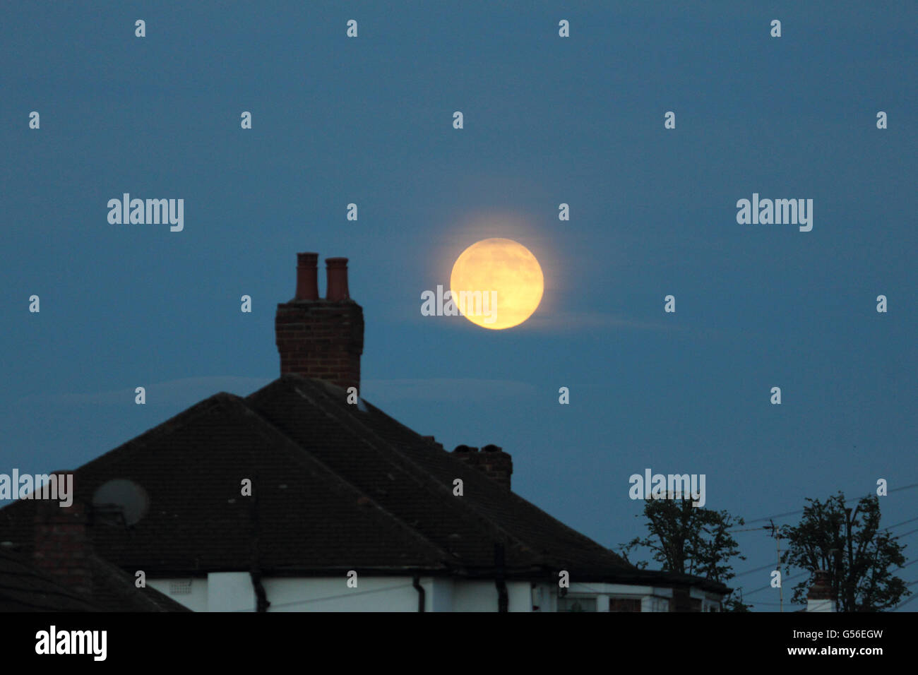 Epsom Surrey, Inghilterra, Regno Unito. Xx Giugno 2016. Il bagliore arancione sopra i tetti della nascente pieno o "luna delle fragole" la sera del solstizio d'estate, come si vede in Epsom Surrey. Credito: Julia Gavin UK/Alamy Live News Foto Stock