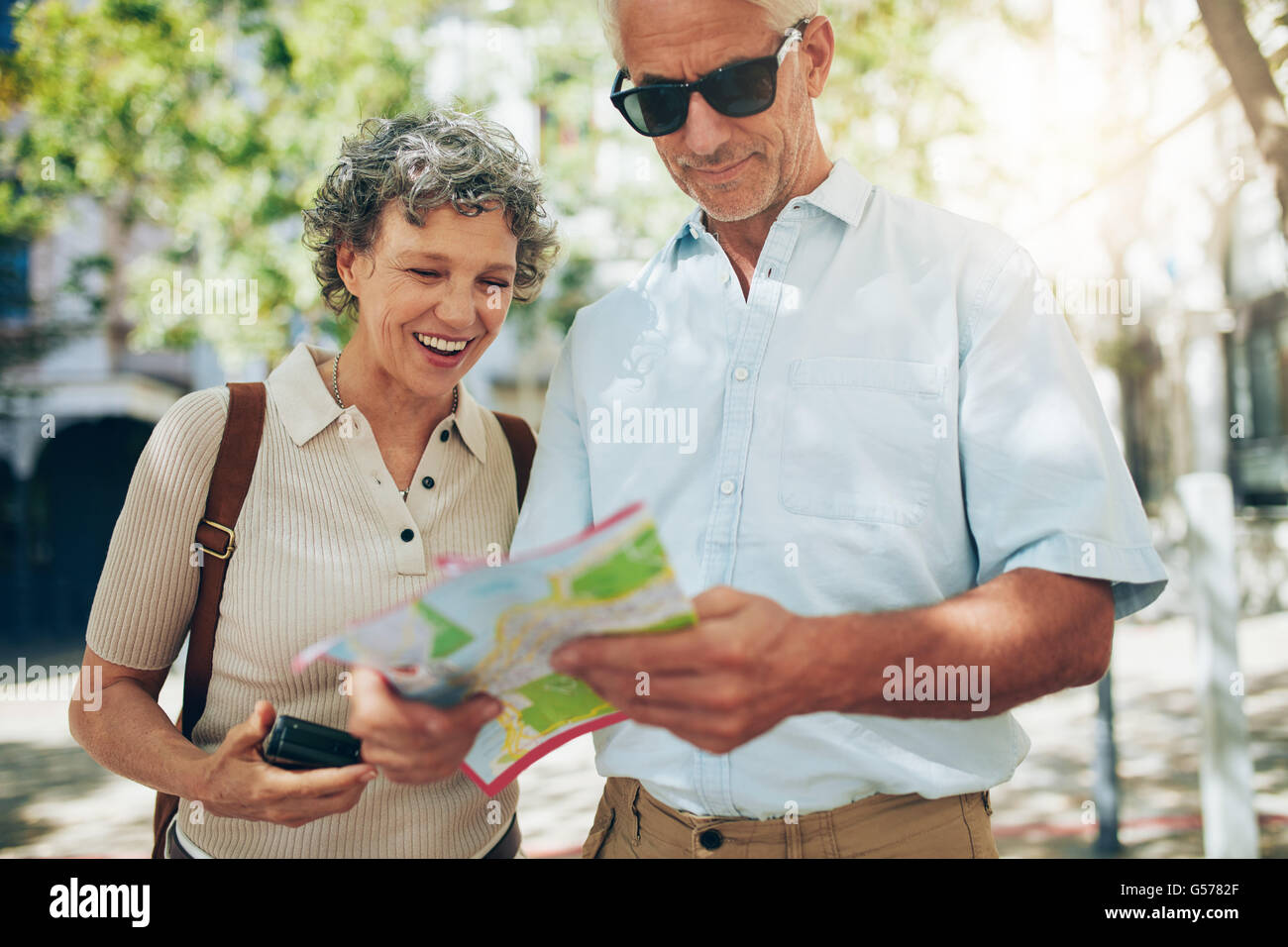 Coppia senior in vacanza la lettura di una mappa. Uomo maturo e la donna cerca di direzione nella città straniera. Foto Stock