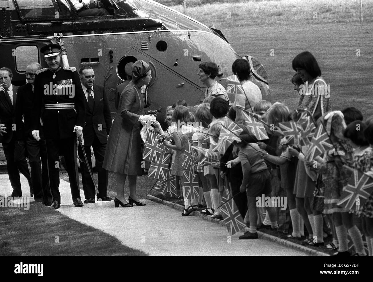 La regina Elisabetta II con bambini che sventolano la bandiera dopo il suo arrivo in elicottero - il suo primo volo in uno - allo storico Castello di Hillsborough, a 14 miglia da Belfast, all'inizio della sua visita Silver Jubilee di 2 giorni a Ulster. E' la prima volta in 11 anni che la Regina visita la Provincia. Foto Stock