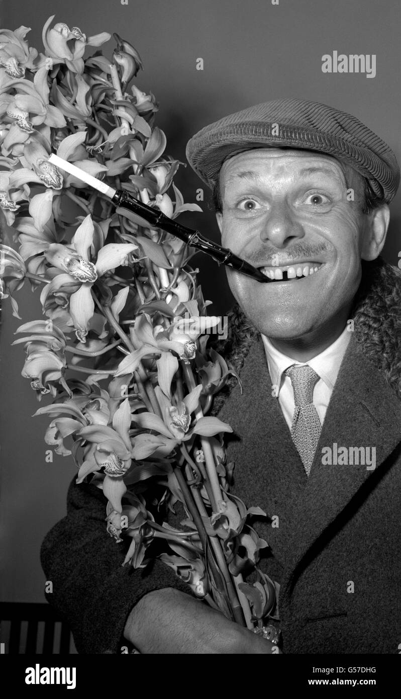 TERRY-THOMAS 1952: L'elegante comico della TV Terry-Thomas, che espone uno stile sartoriale distintivo, ritorna da una vacanza a Madeira con un cappello e un porta sigarette esteso. Porta un cespuglio di orchidee per sua moglie. È raffigurato a Southampton. Foto Stock