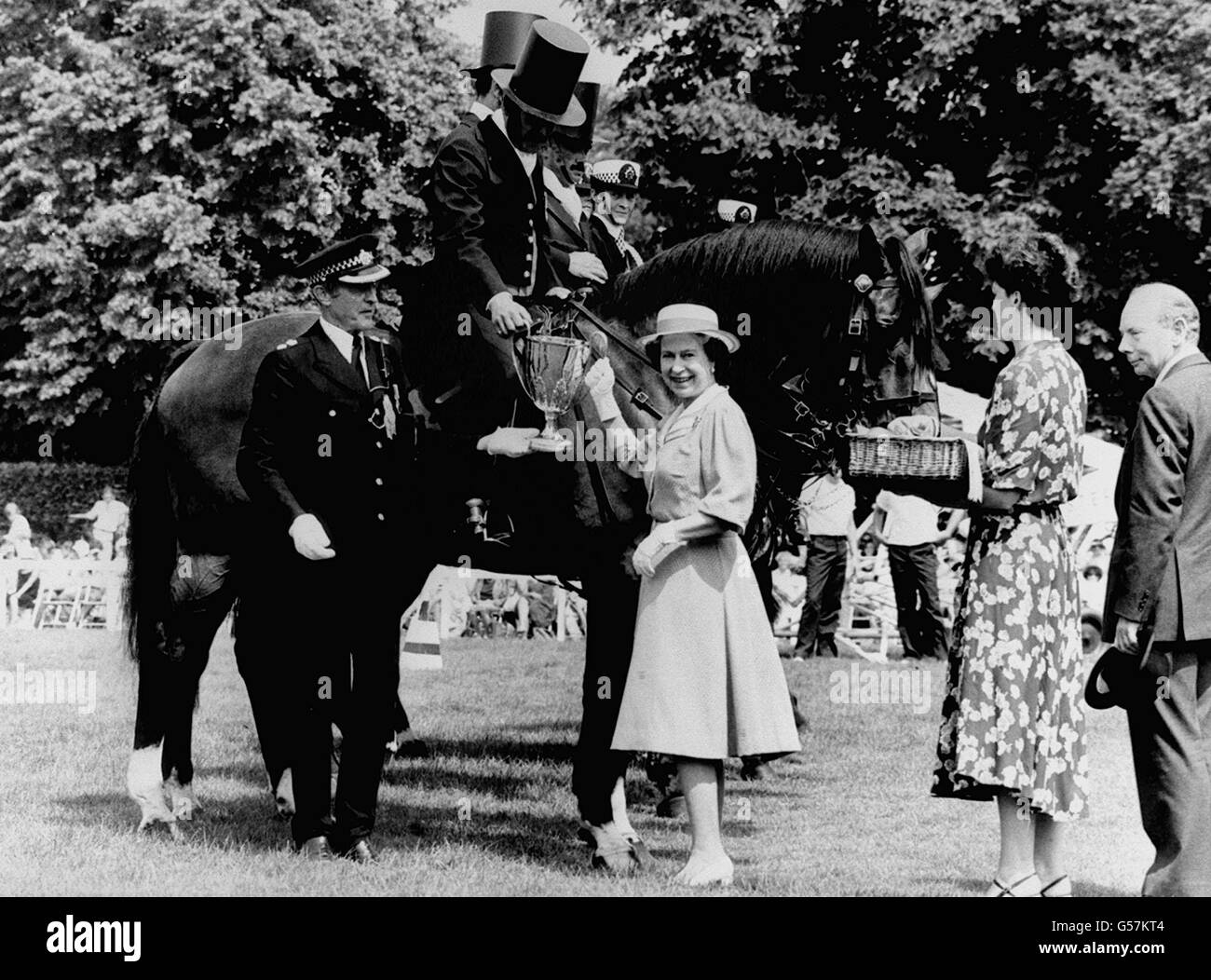La regina Elisabetta II presenta la coppa dei vincitori per il 'miglior gruppo di 3 ufficiali e cavalli' a 'Peeler' PC David Edwards, della stazione di Hyde Park ad una mostra di cavalli a Imber Court, Surrey. Lo spettacolo celebra il 150° anniversario della sede della polizia metropolitana. Foto Stock