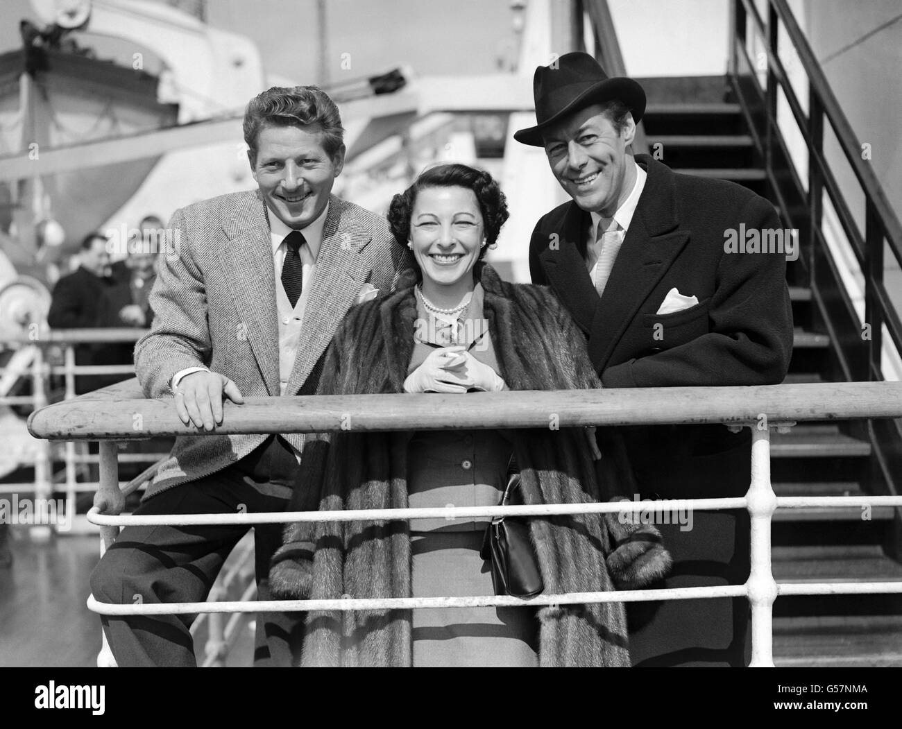 Danny Kaye, sua moglie Sylvia, e la star del cinema britannica Rex Harrison alla ringhiera della "Regina Elisabetta" al suo arrivo a Southampton. Foto Stock