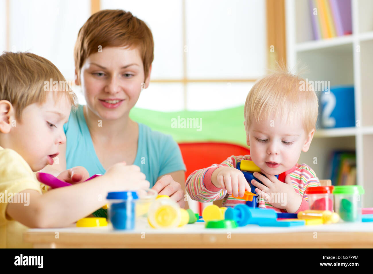 Donna insegna ai bambini artigianato in asilo nido o playschool Foto Stock