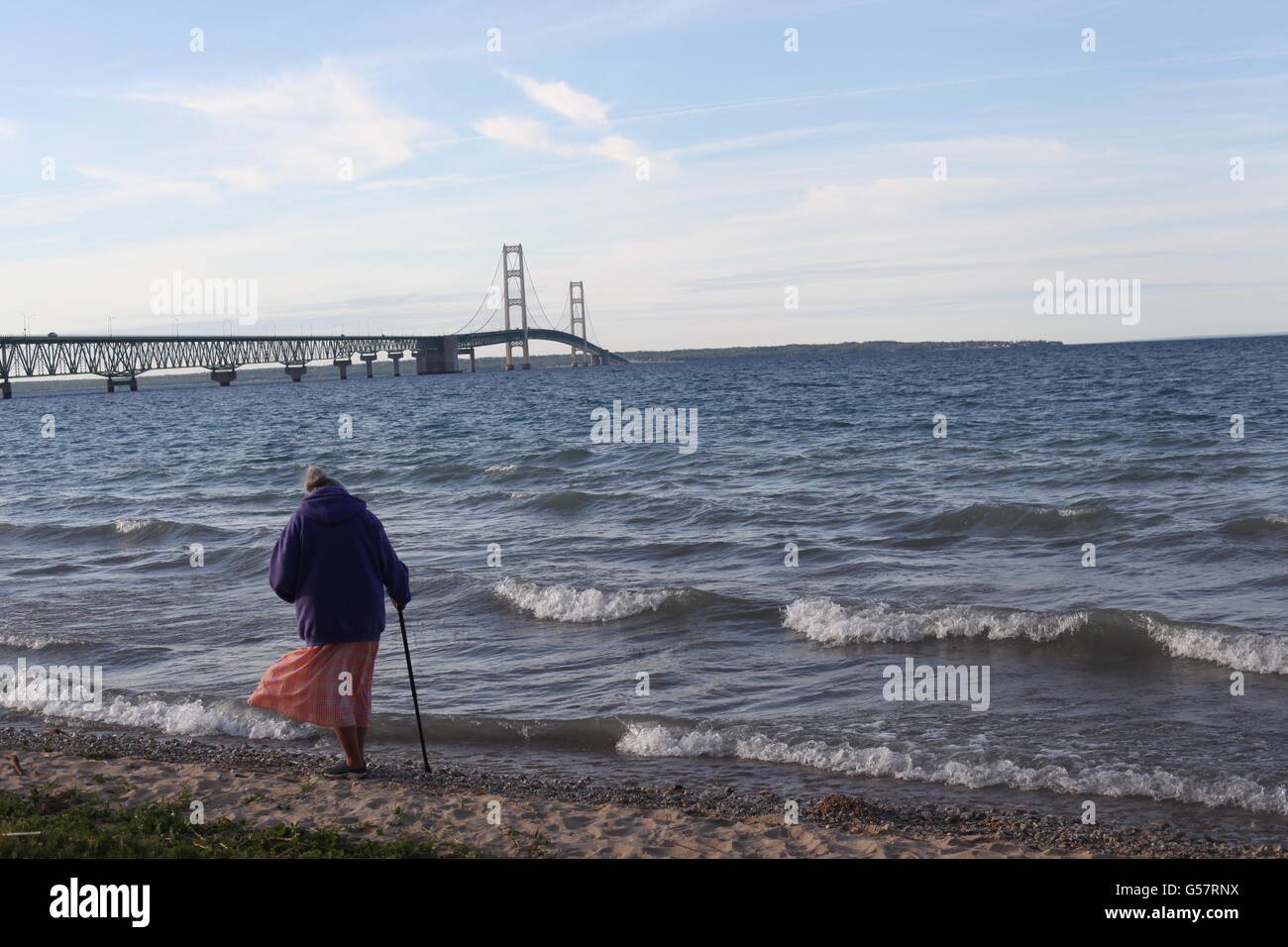 Ponte Mackinaw nel Michigan con la vecchia donna con canna a piedi sulla spiaggia con la riva del lago Michigan Foto Stock