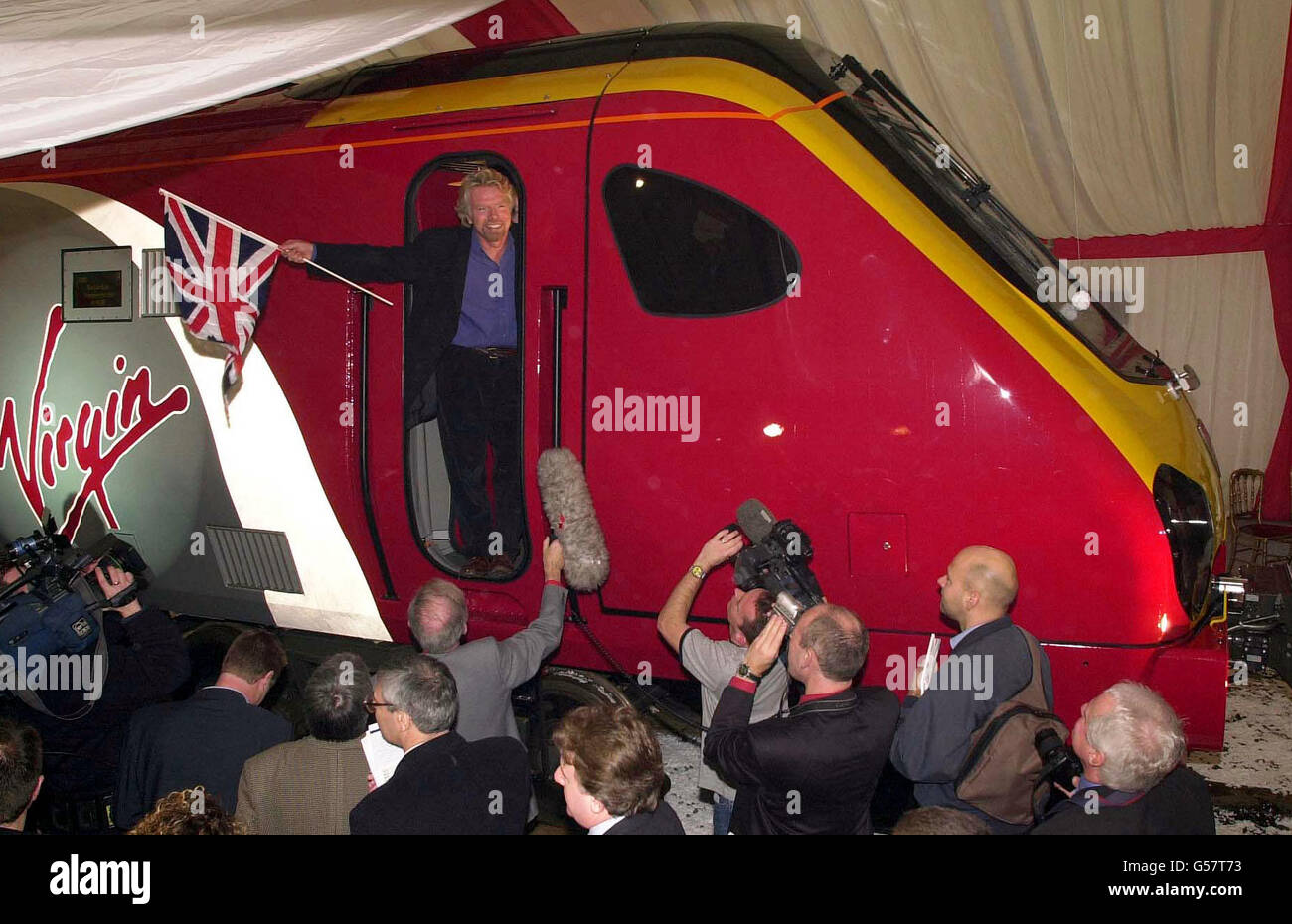 Sir Richard Branson sventola la bandiera dell'Unione durante il lancio del suo nuovo treno Virgin Maiden Voyager a Bruges, Belgio. *05/03/01 le tariffe ferroviarie sui treni Virgin aumenteranno di quasi il 10% a causa del disastro di Hatfield, ha confermato la società. I passeggeri che hanno subito mesi di ritardi sulla rete ferroviaria dovranno pagare i prezzi dei biglietti aumentati a partire da maggio. Virgin ha dichiarato di deplorare l'aumento e di incolpare Railtrack per non aver fornito un adeguato risarcimento per i disagi causati dal crash di Hatfield. Foto Stock