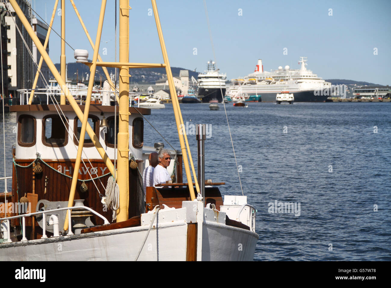 Il vecchio peschereccio di fronte delle moderne navi da crociera. Porto di Bergen, Norvegia Foto Stock