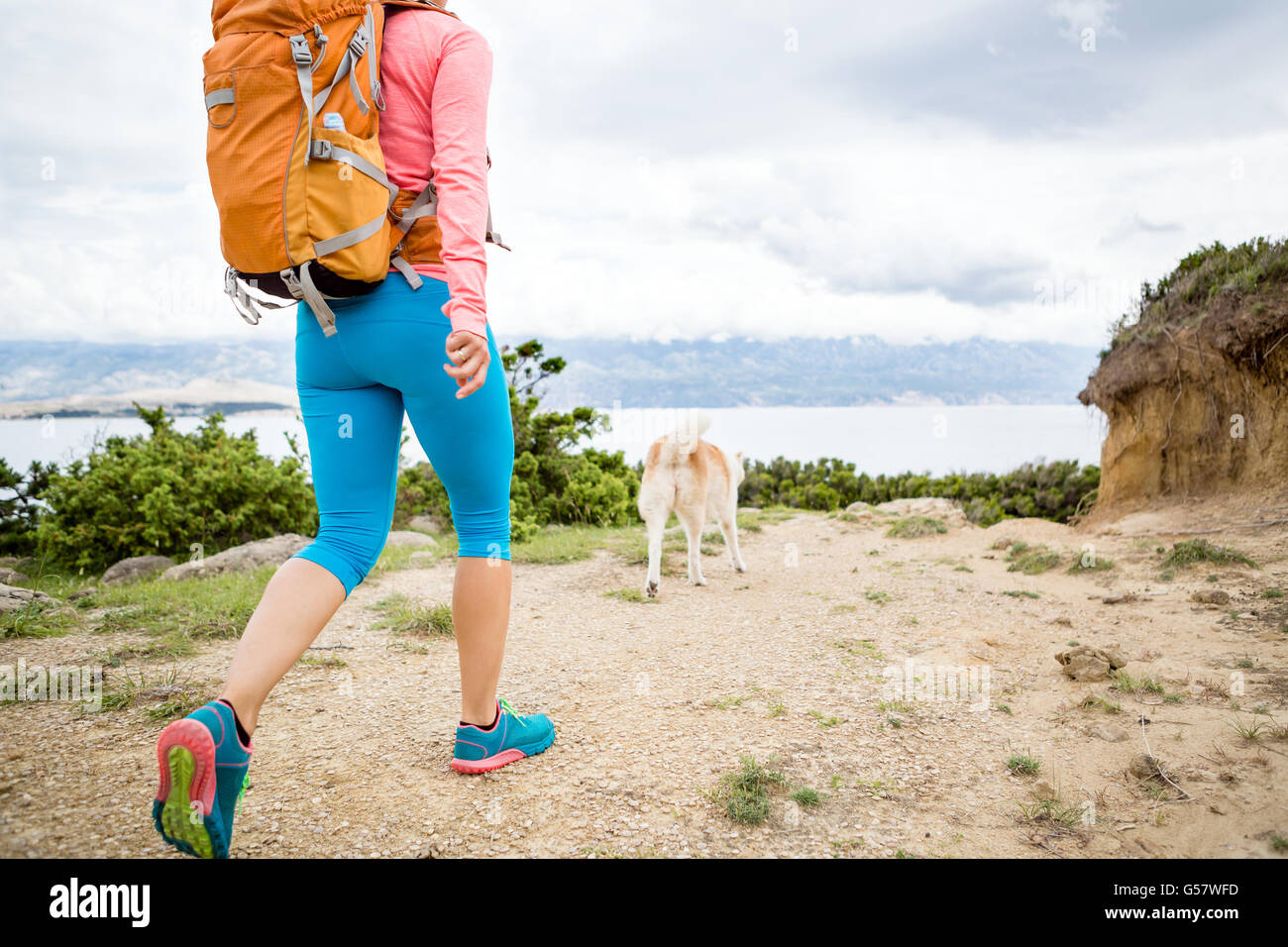 Donna escursionismo con akita inu cane sul sentiero sul mare. Ricreazione e uno stile di vita sano all'aperto in estate sulle montagne e mare natura. Foto Stock
