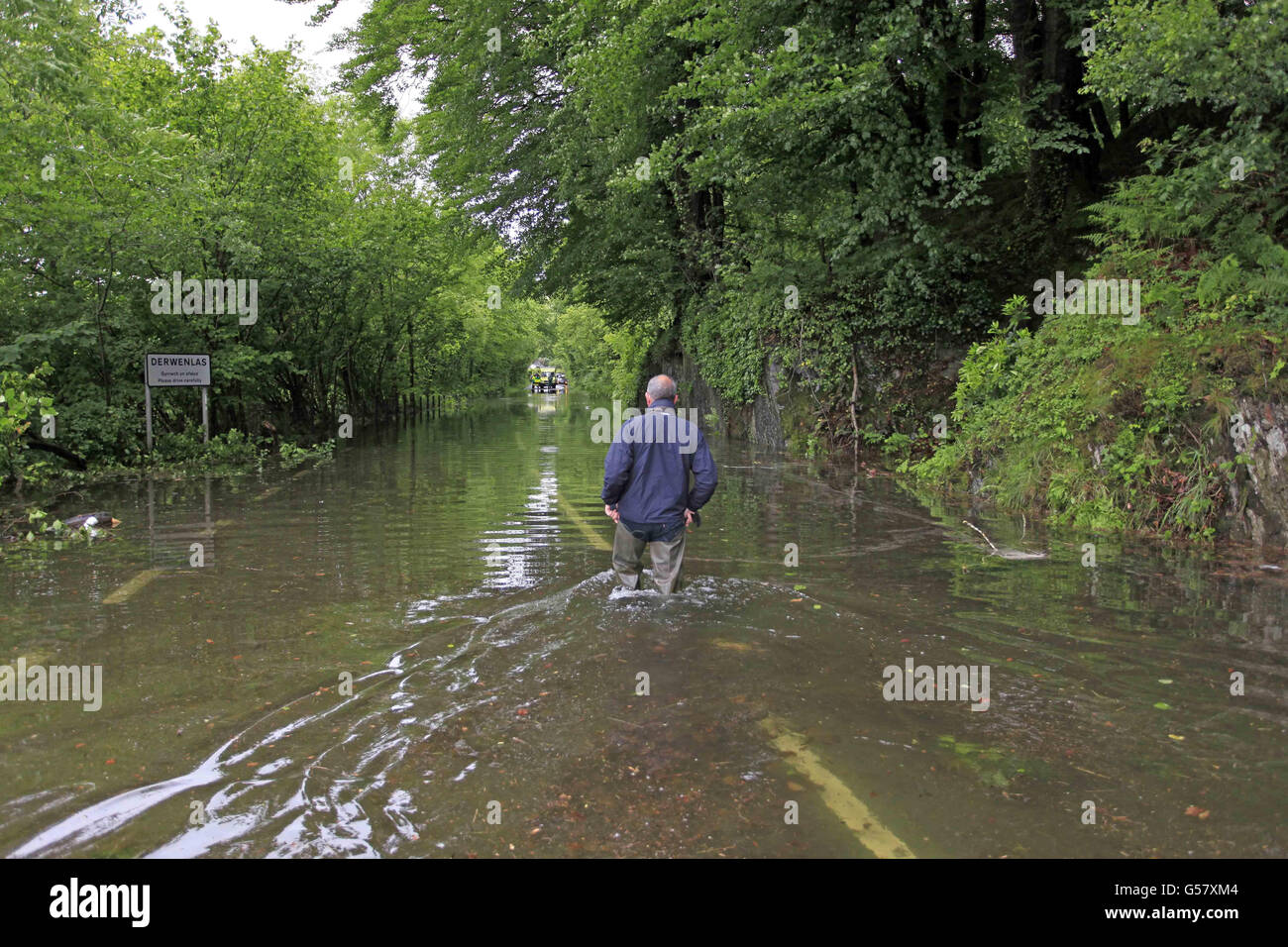 Un uomo cammina attraverso le acque alluvionali a Machynlleth a Powys, Galles, dopo gravi inondazioni che hanno colpito il Galles occidentale. Foto Stock