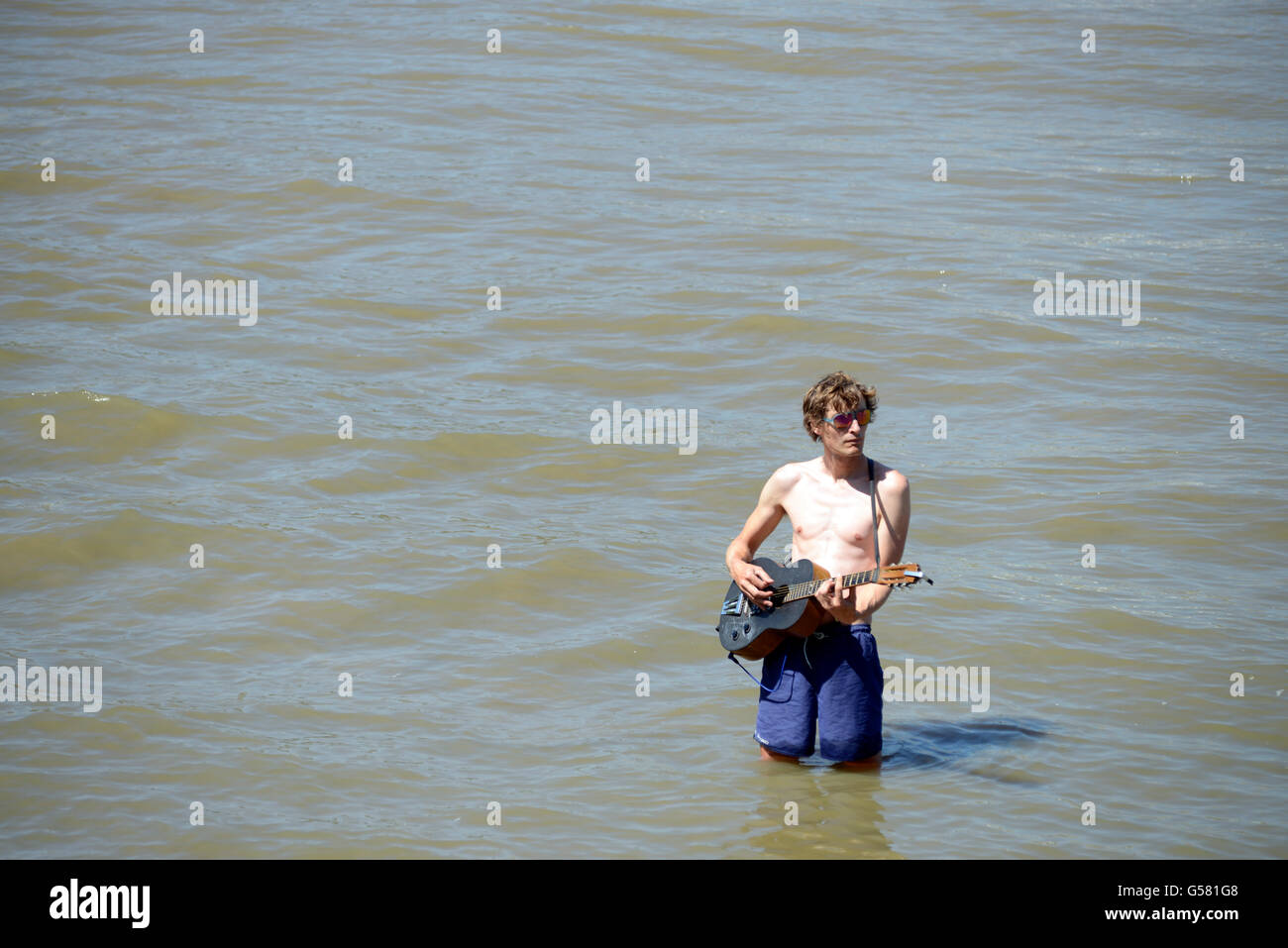 Busker divertente folle sulla banca del sud a suonare la chitarra nel fiume Thames, London. Foto Stock