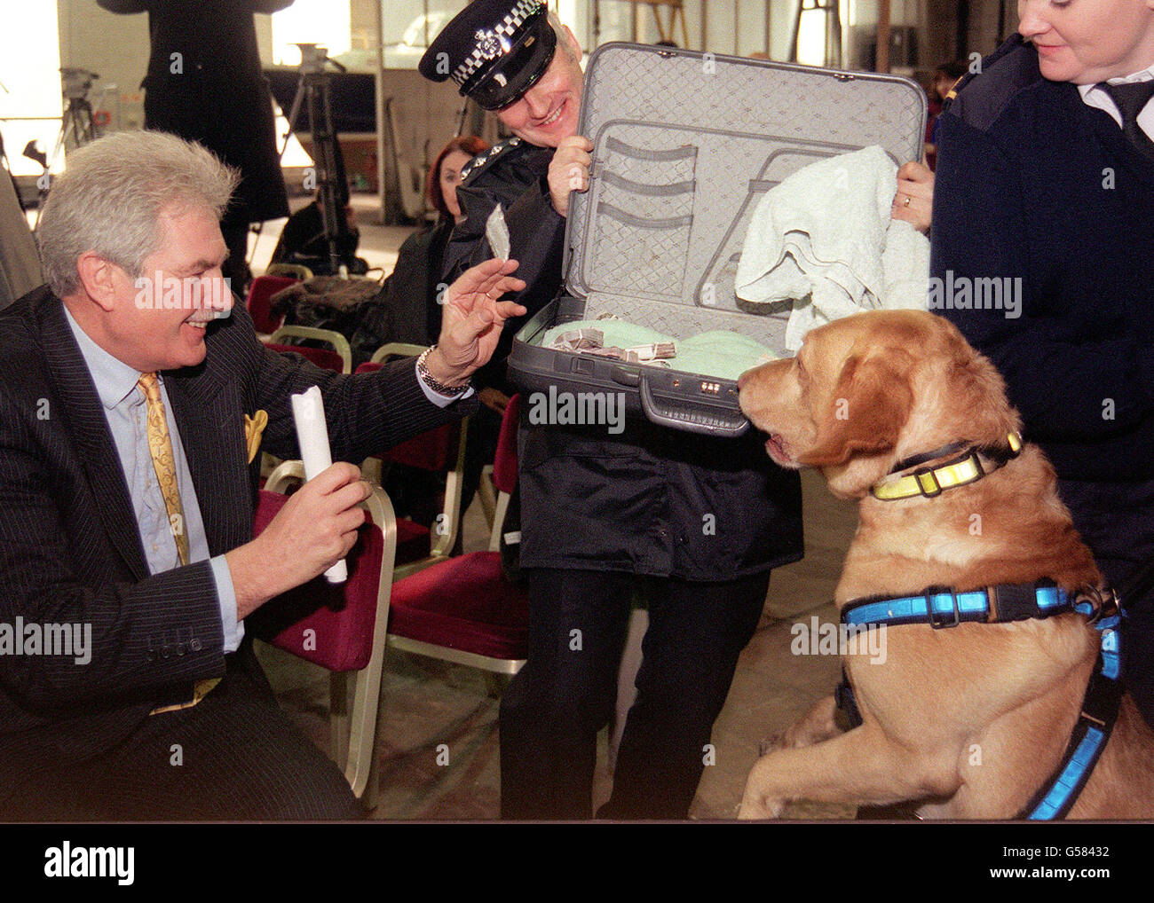 Il Coordinatore britannico per la lotta contro le droghe Keith Hellawell (a sinistra) ondeggia un pacchetto di polvere di anfetamina dopo essere stato 'infettato' da un cane da cecchino durante una dimostrazione della Metropolitan Police Dog Unit, a Londra, per segnare la pubblicazione del World Drug Report 2000 dell'ONU. Foto Stock