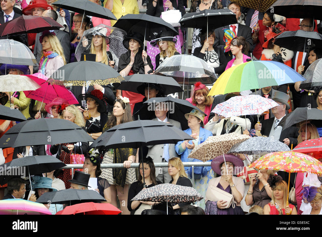 I Racegoers riparano dalla pioggia mentre aspettano l'arrivo della regina Elisabetta durante il giorno tre del raduno reale di Ascot 2012 all'ippodromo di Ascot, Berkshire. Foto Stock