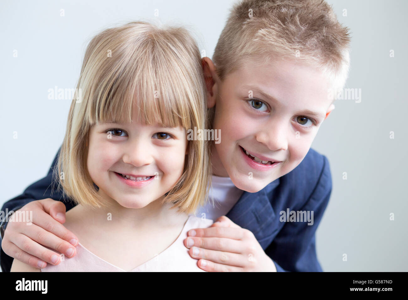 Ragazzo e ragazza vestita formalmente e posa per la fotocamera insieme su uno sfondo bianco Foto Stock