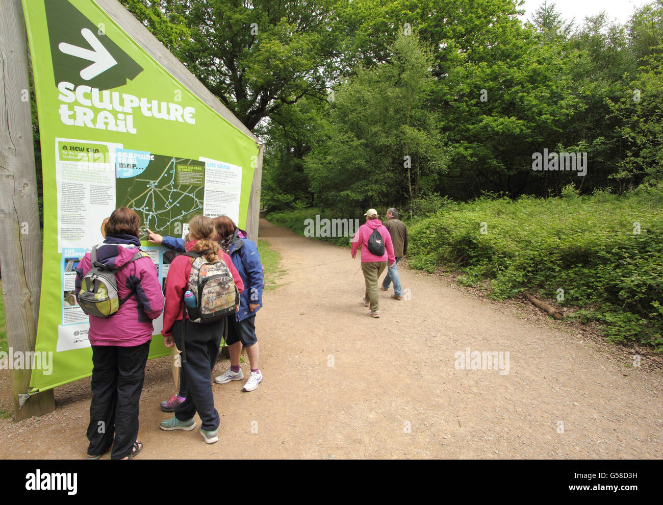 Visitatori guarda la scheda informazioni all'inizio del sentiero delle sculture nella Foresta di Dean vicino a Coleford - fine Maggio Foto Stock