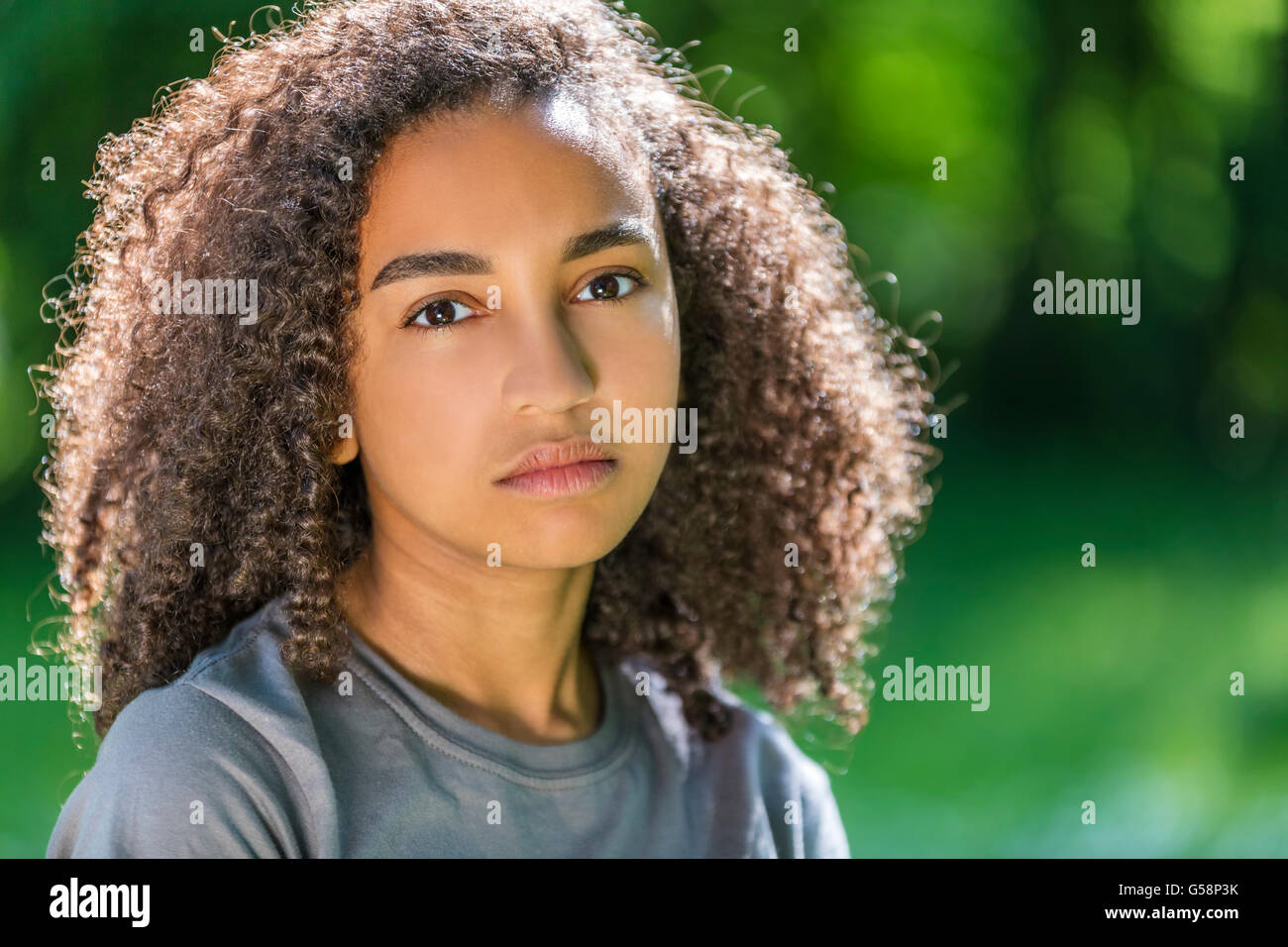 Considerato razza mista americano africano ragazza adolescente femmina giovane donna fuori in primavera o in estate guardando triste premuto Foto Stock