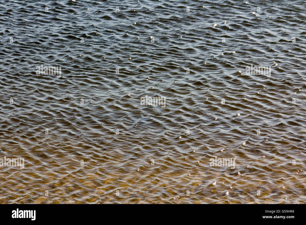 Sfondo con acqua cristallina e piccole onde e rocce Foto Stock