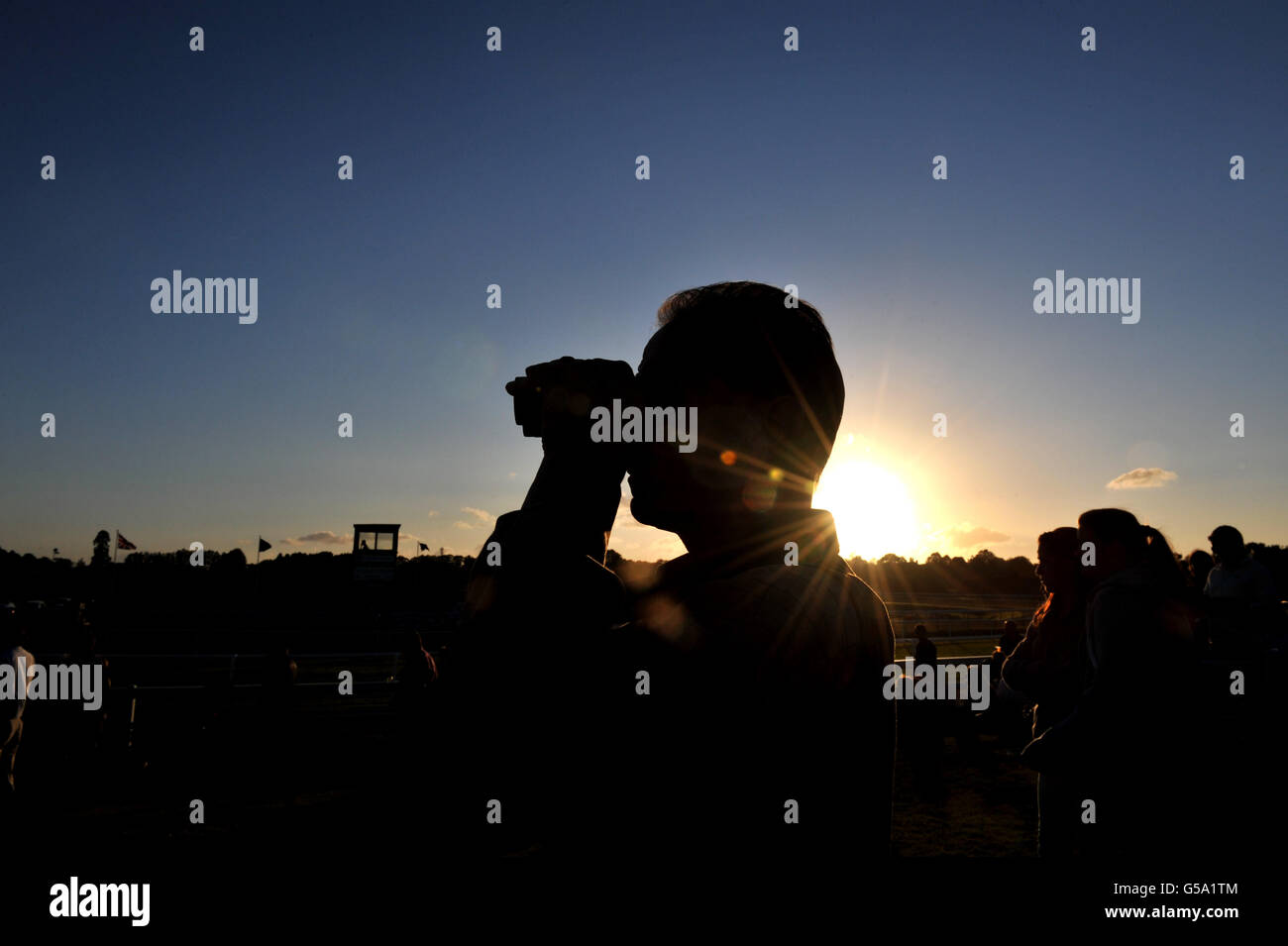 Racegoers guarda l'azione mentre il sole tramonta all'ippodromo di Lingfield Park Foto Stock