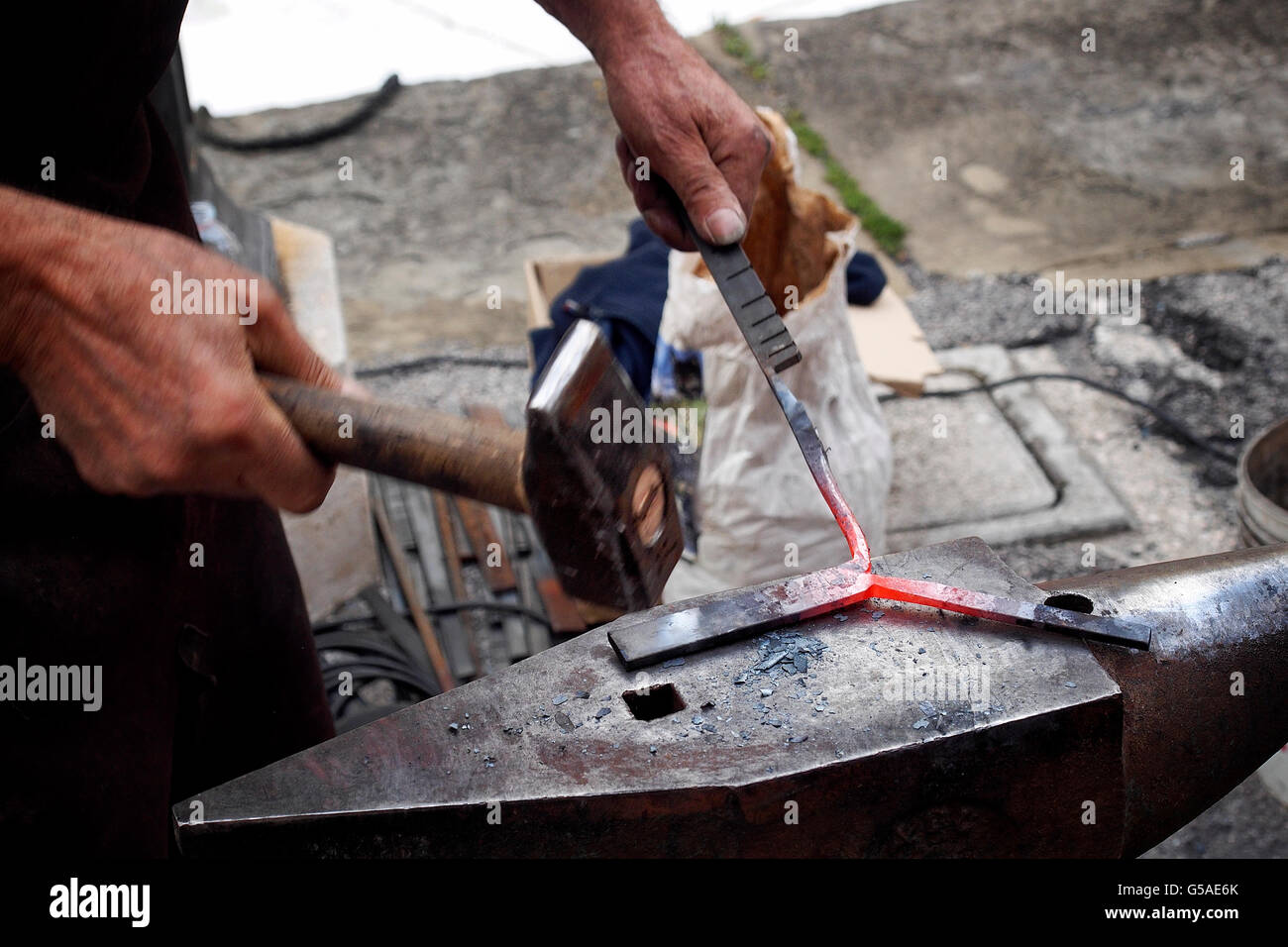Colpisce un pezzo di ferro caldo su un' incudine con il martello. Foto Stock