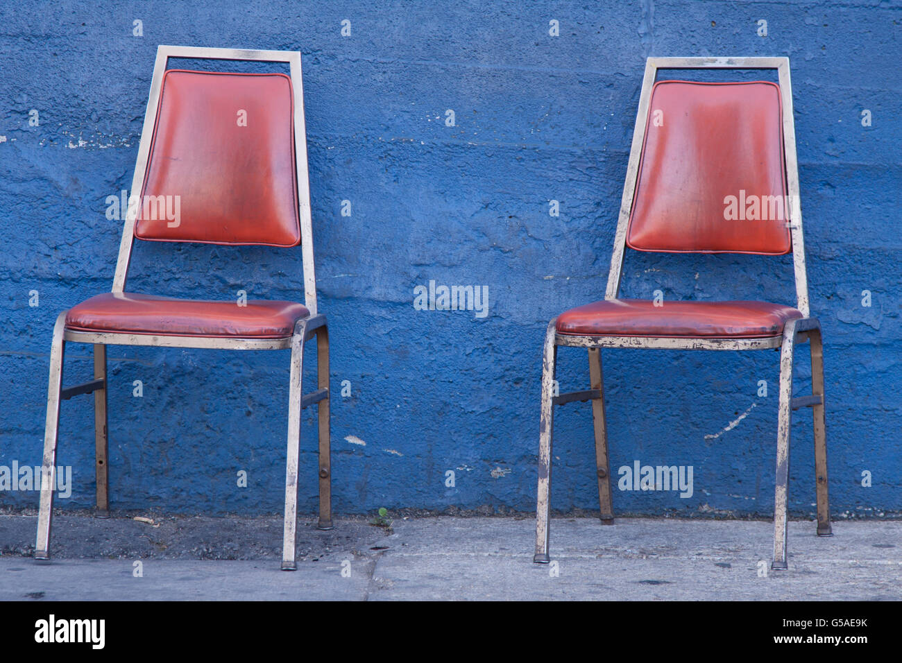 Due sedie rosse contro la parete blu Foto Stock