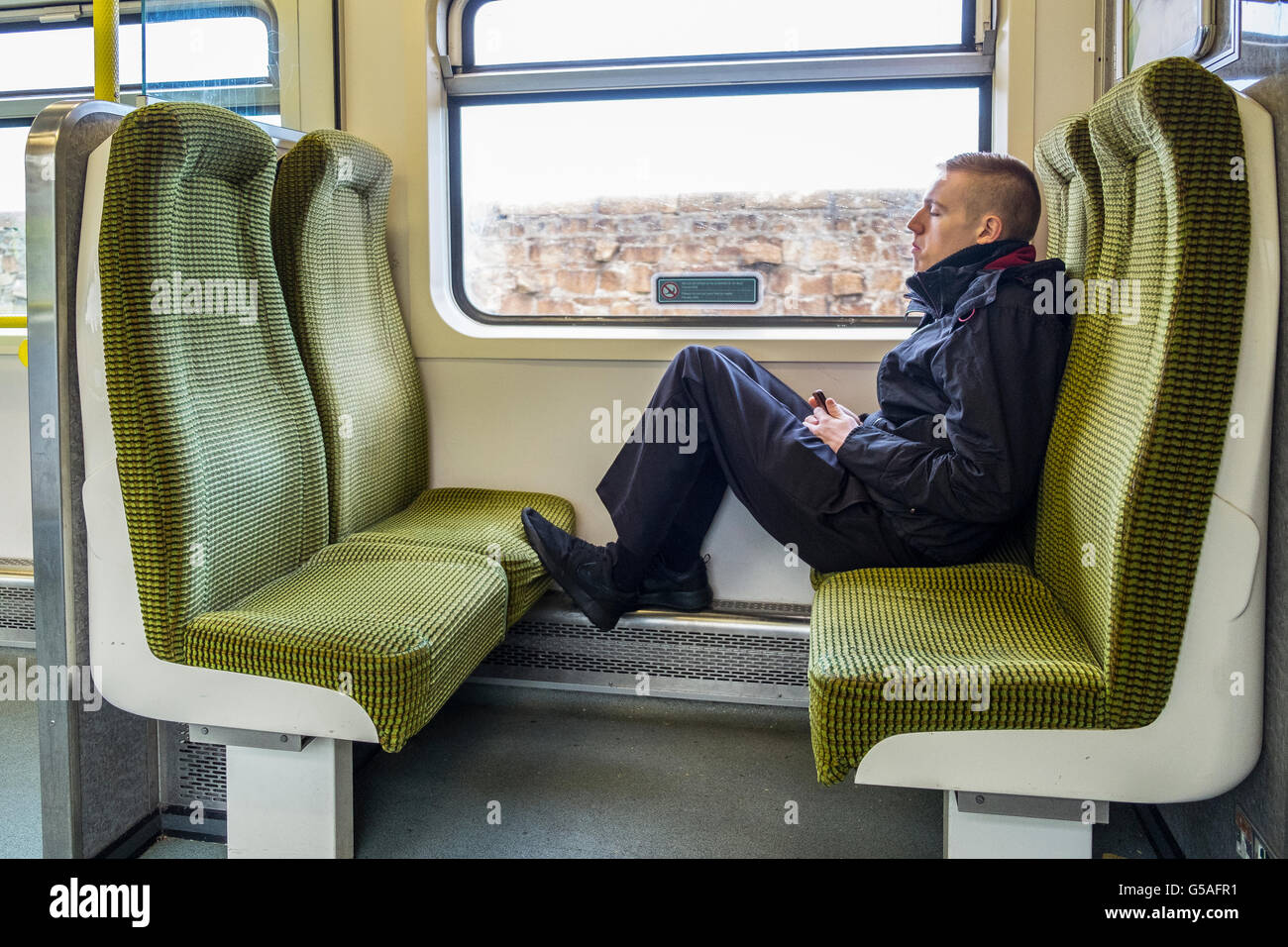 Giovane uomo piedi piedi sedili sedile vagone ferroviario REGNO UNITO Foto Stock