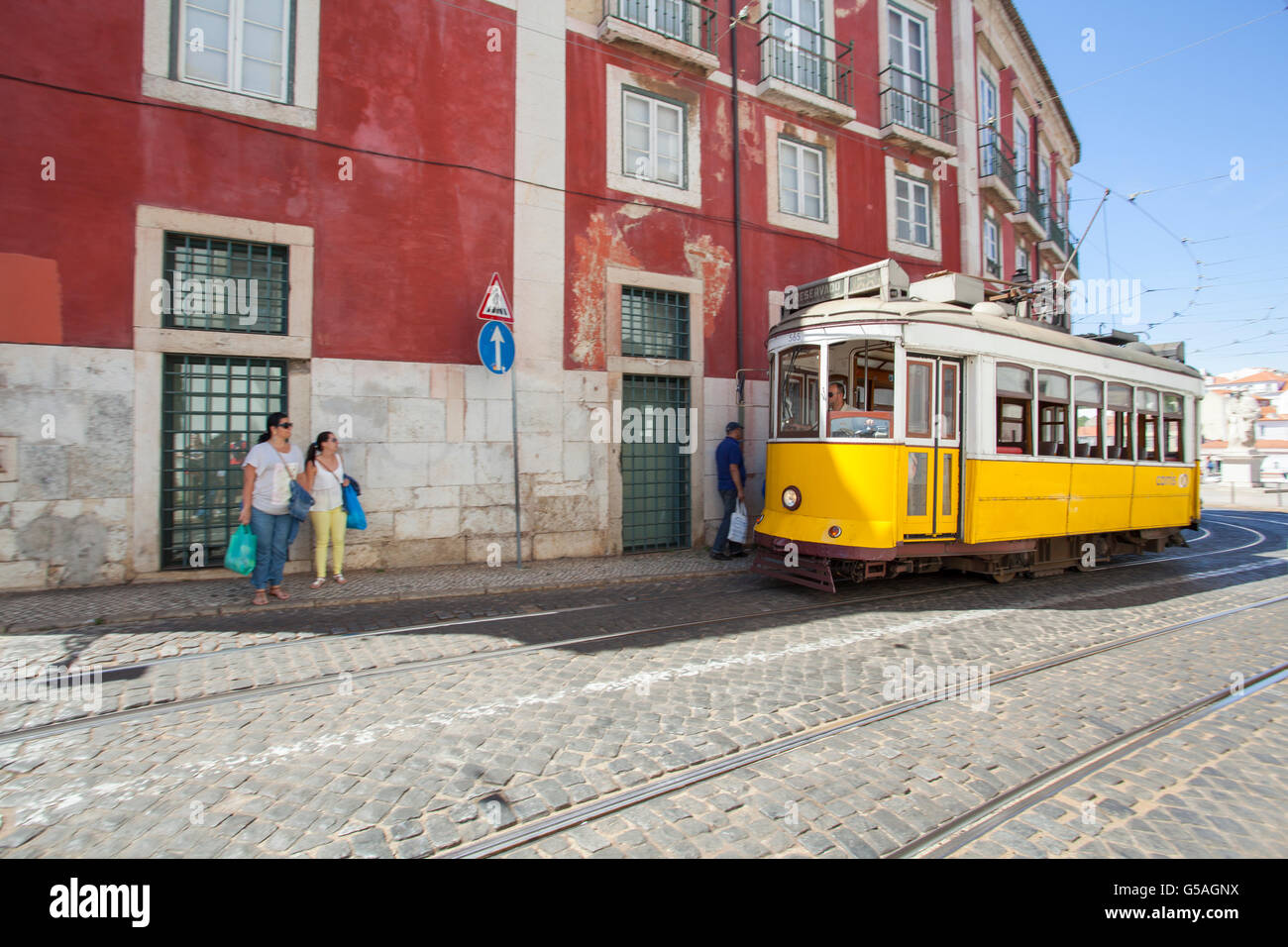 Il tram giallo 28 arrotondamento di un angolo nel quartiere di Alfama a Lisbona, Portogallo Foto Stock