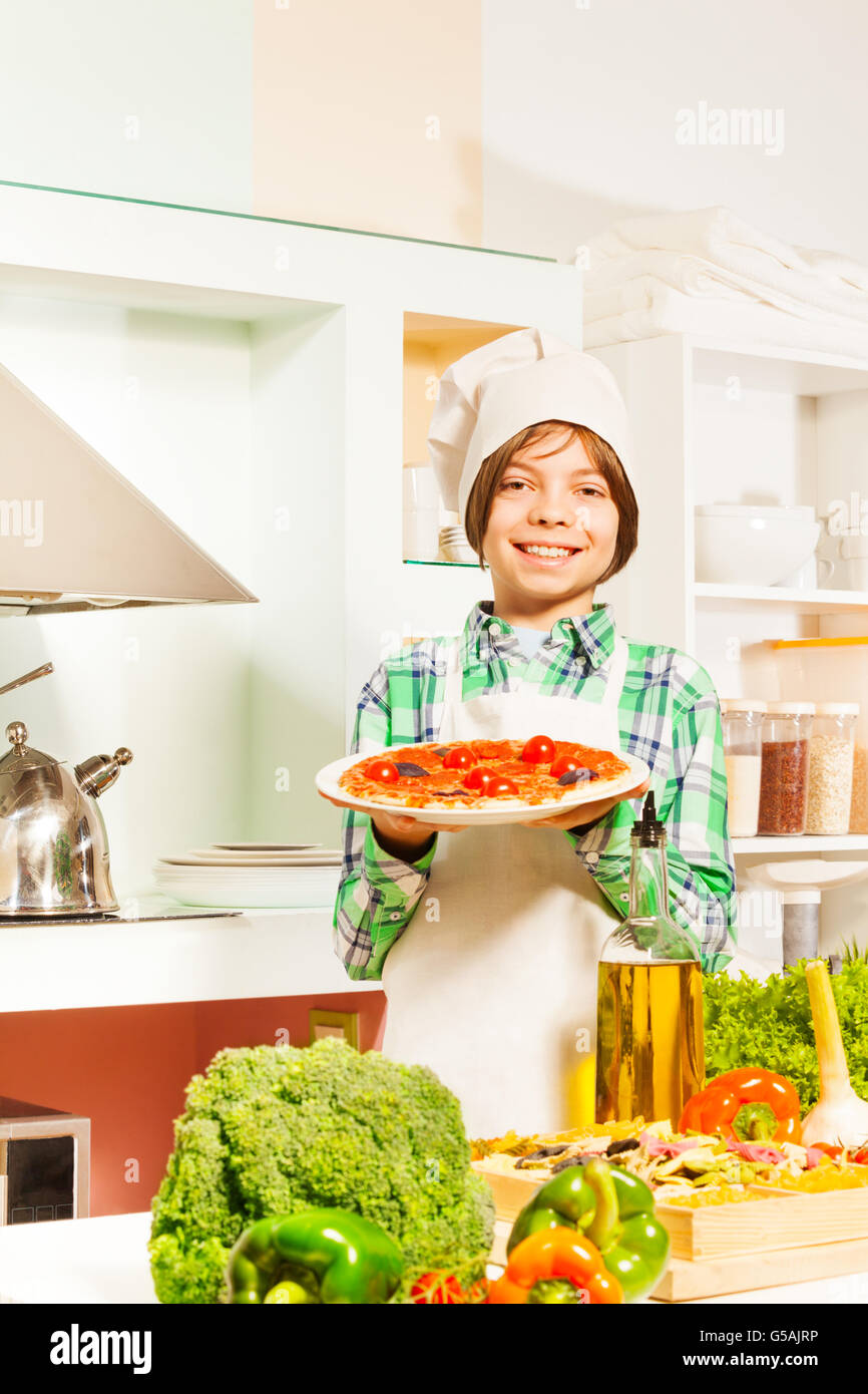 Giovane cuoco con una gustosa pizza in cucina Foto Stock