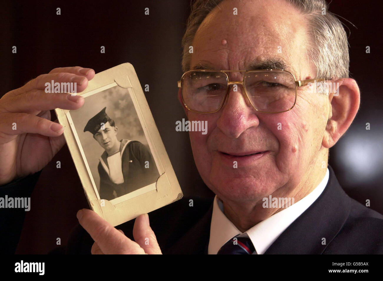 Il veterano di Dunkerque Albert 'Joe' Barnes con una fotografia di se stesso come marinaio di 18 anni. L'ex pilota di autobus di 75 anni ha ricevuto una medaglia al Golden Hero Awards di Londra, dopo aver atteso più di 60 anni per il riconoscimento del suo eroismo. * ...dopo aver salvato centinaia di soldati britannici sulle spiagge di Dunkerque come un ragazzo di 14 anni che lavorava su un rimorchiatore durante la seconda guerra mondiale. Foto Stock