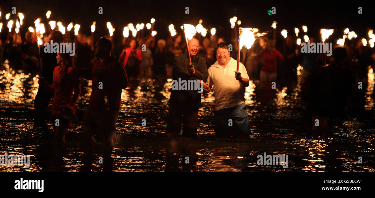 Alcuni dei 2,012 portatori di torcia si preparano ad entrare nel mare al largo della Weymouth Esplanade come parte del loro festival "Battaglia dei Venti", che coincide con la regata olimpica nella vicina baia di Weymouth. Foto Stock