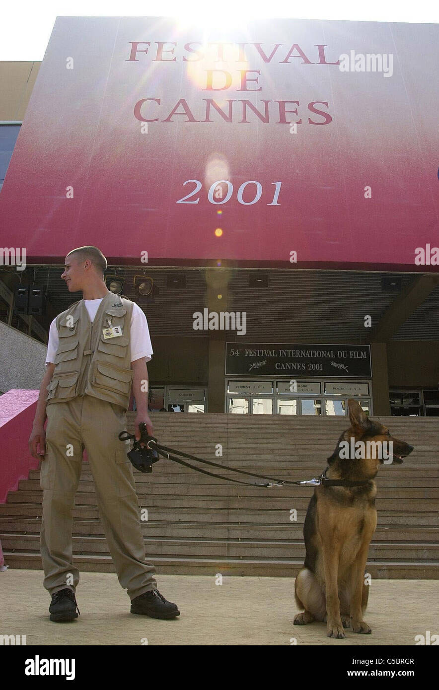 Un ufficiale di sicurezza e un cane tengono la guardia sul famoso ingresso del tappeto rosso (che è ancora da posare) al di fuori del Palais des Festivals, al Festival del Cinema di Cannes, in Francia. * la vetrina annuale di film glamour che ospita alcuni dei più grandi nomi nell'industria cinematografica, e si prevede di attrarre circa 40,000 visitatori. Una serie di film ribaltati per il successo della biglietteria sarà ufficialmente svelata durante il festival di due settimane. Foto Stock