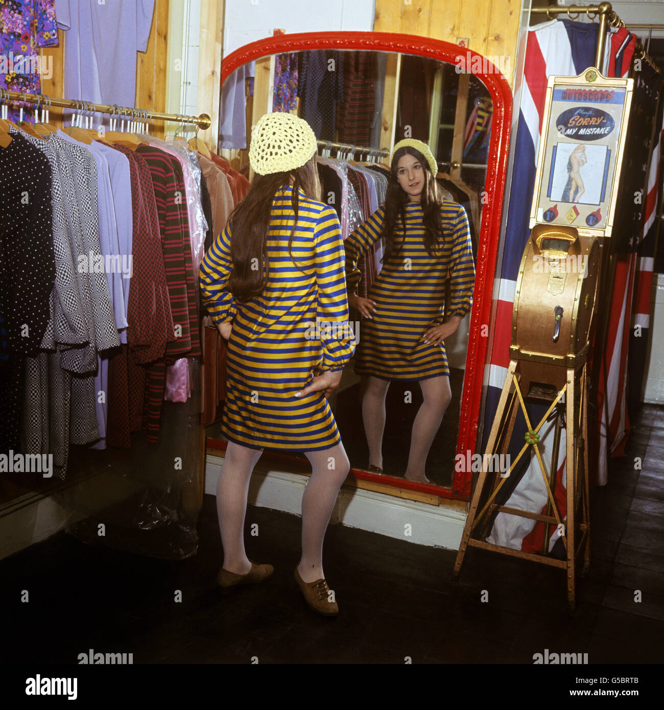 Il cliente Jackie Binder, in un nuovo abito 'in stile di condanna' disegnato da Pauline Fordham, guarda nello specchio la boutique di Miss Fordham a Ganton Street, nei pressi di Carnaby Street, Londra. Foto Stock