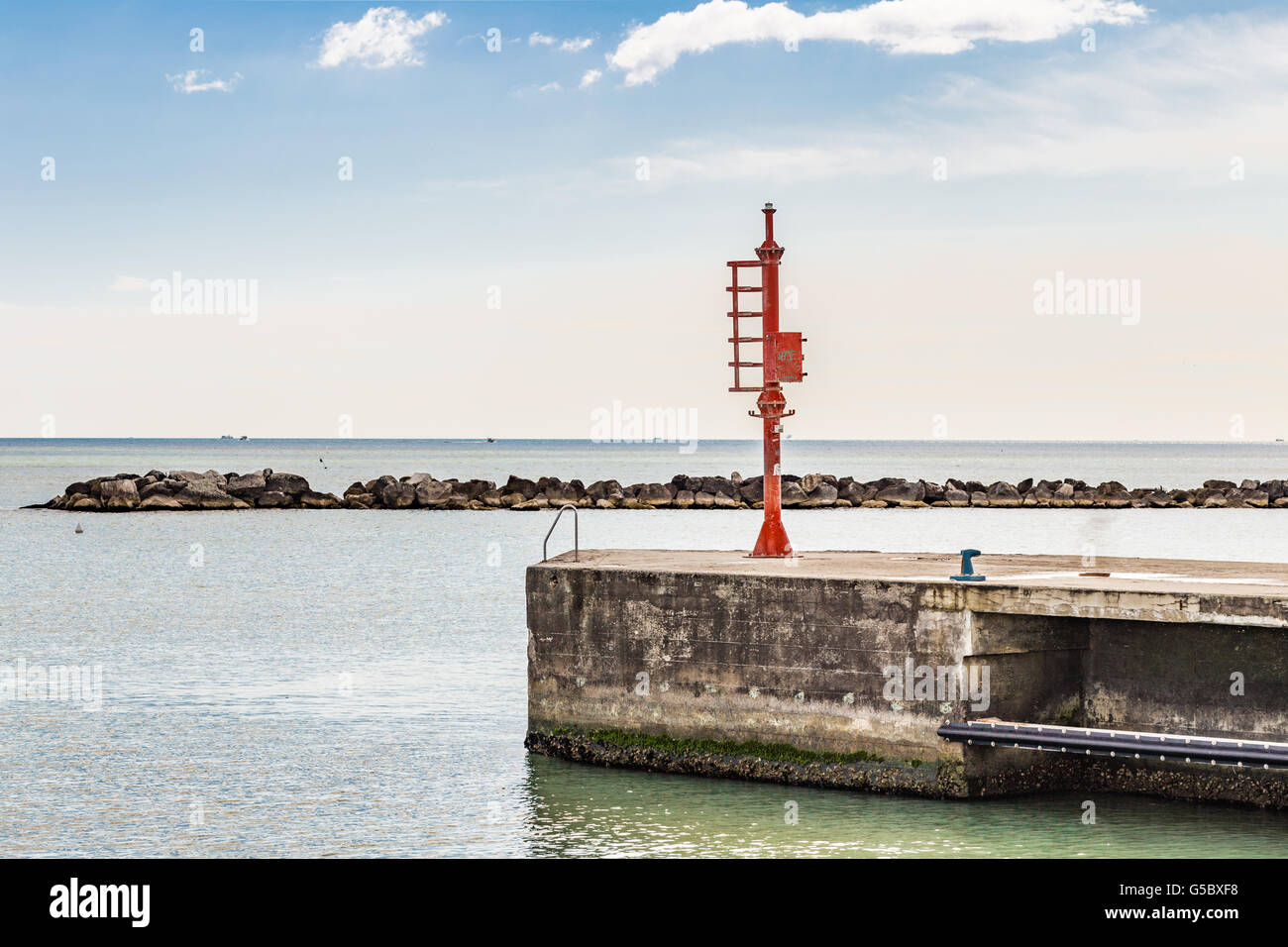 Faro rosso su un molo nella parte anteriore del gruppo di rocce frangiflutti fuori della costa adriatica Foto Stock