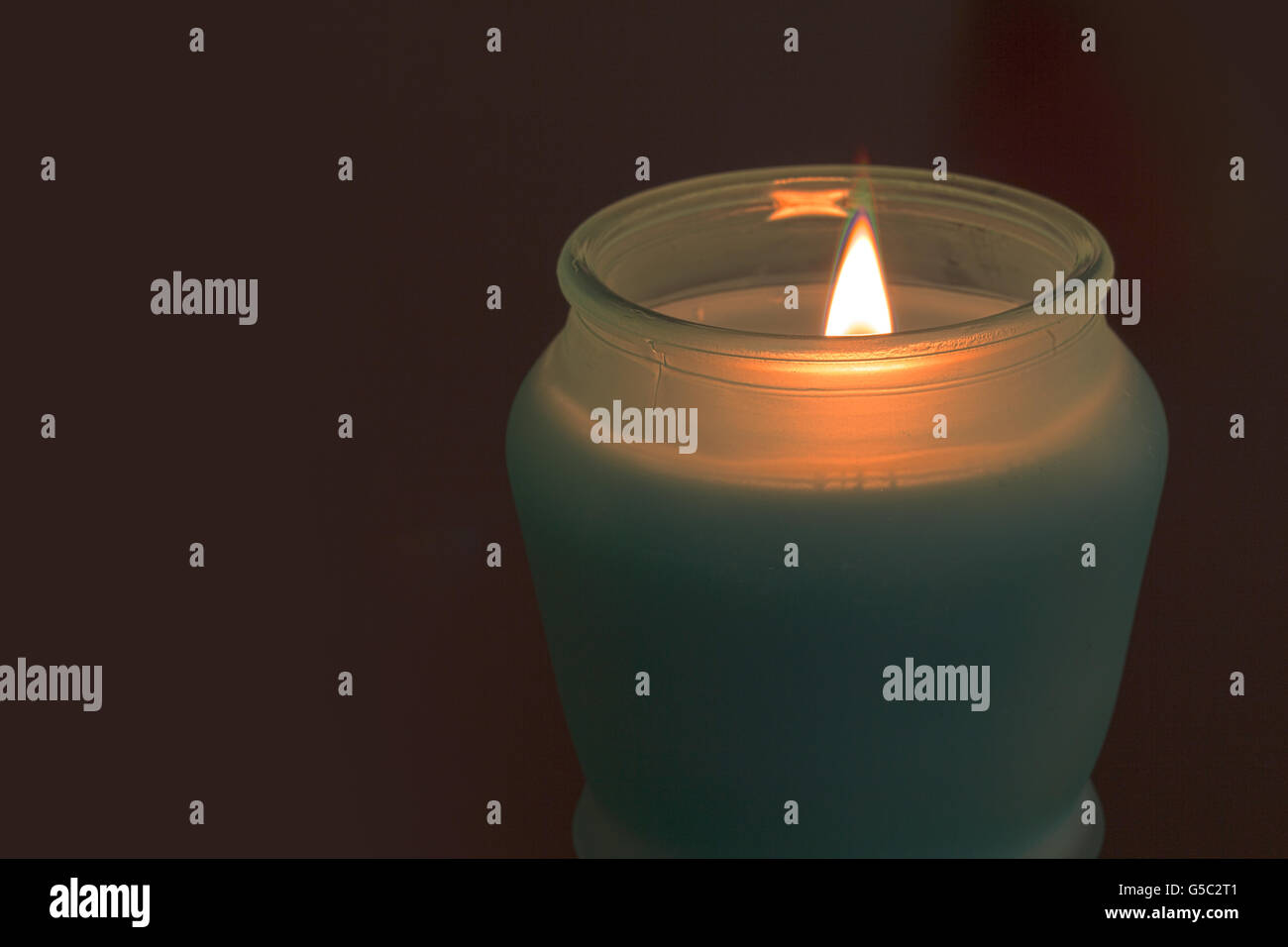 Una candela si illumina al buio, fornendo una stanza con bassa luce romantica Foto Stock