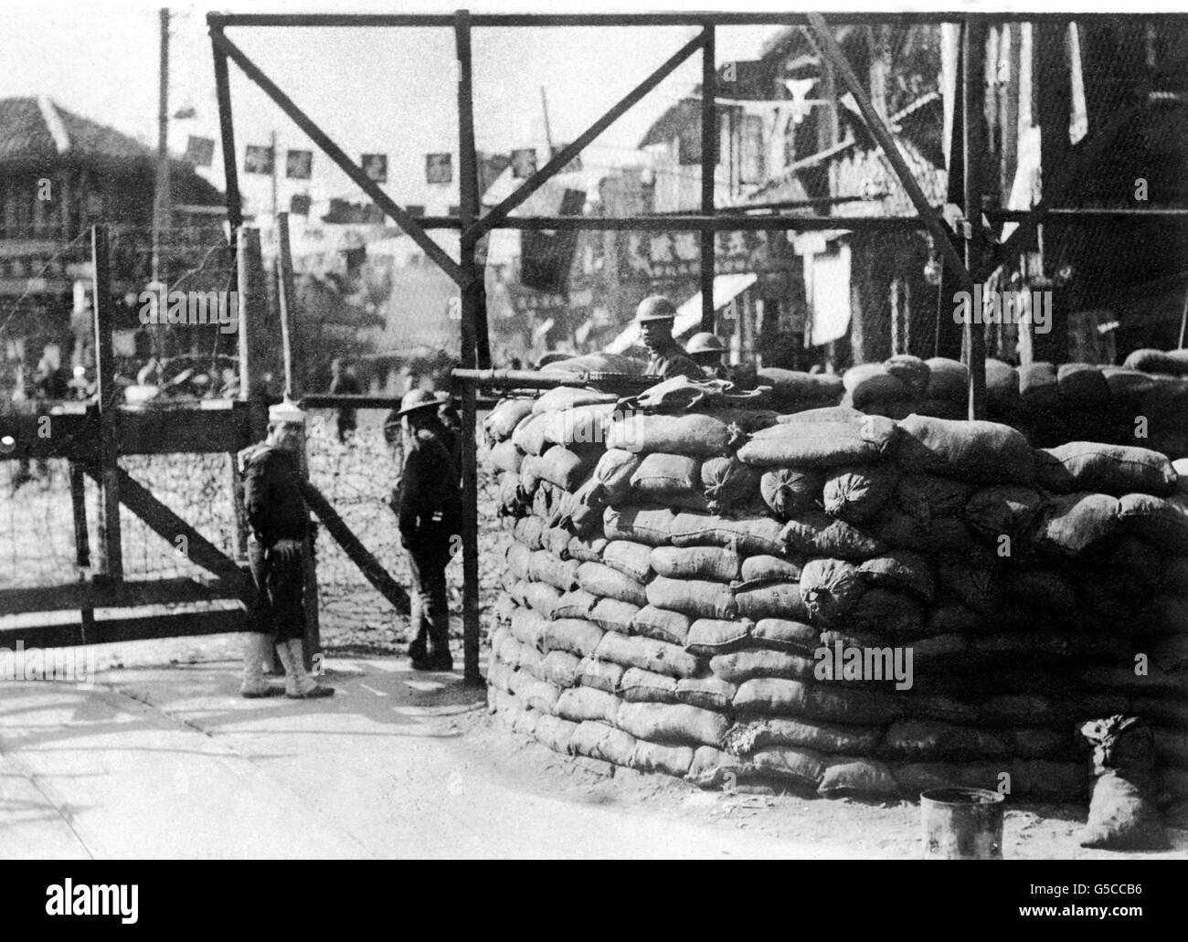 Avamposto difensivo britannico nel quartiere internazionale della città portuale cinese di Shanghai, con uomini del reggimento Gloucestershire. Un marinaio americano di una delle due navi da guerra statunitensi nel porto, si alza e parla con uno dei Glosters. Foto Stock