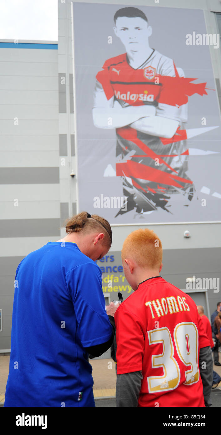 I fan di Cardiff che indossano sia la divisa rossa che quella blu si trovano di fronte allo stadio prima del campionato Npower Football League al Cardiff City Stadium di Cardiff . Foto Stock