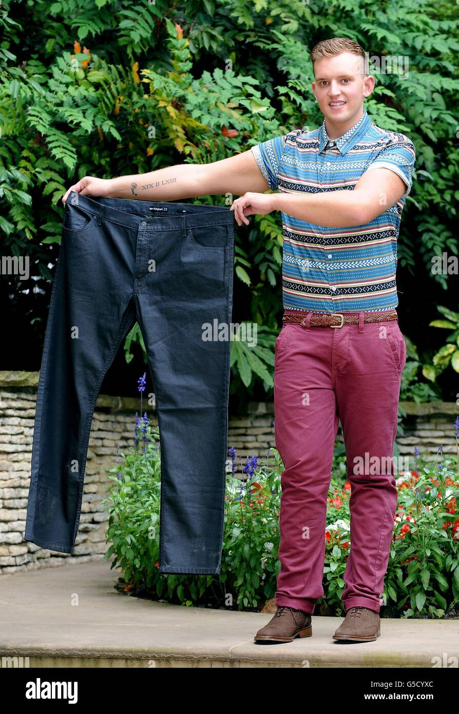 Tom Jones, 18 anni, di Grappenhall, Warrington, che ha vinto lo Slimming World's Young Slimmer of the Year 2012, dopo aver perso 5st 2lbs, tiene un paio dei suoi pantaloni prima della sua perdita di peso. Foto Stock