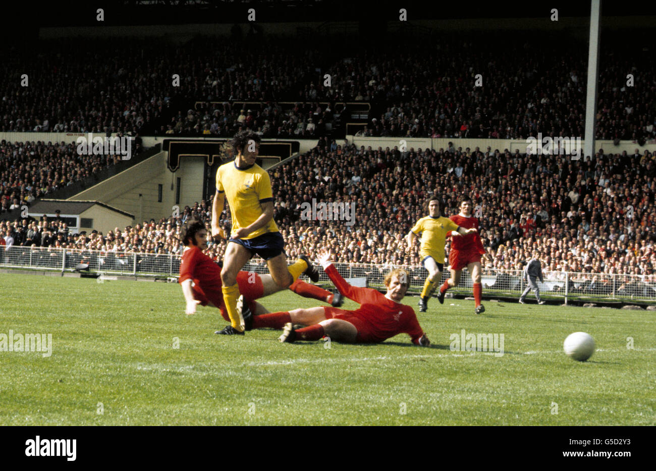 Il raggio Kennedy dell'Arsenal lascia Larry Lloyd e Alec Lindsay di Liverpool a terra. Foto Stock