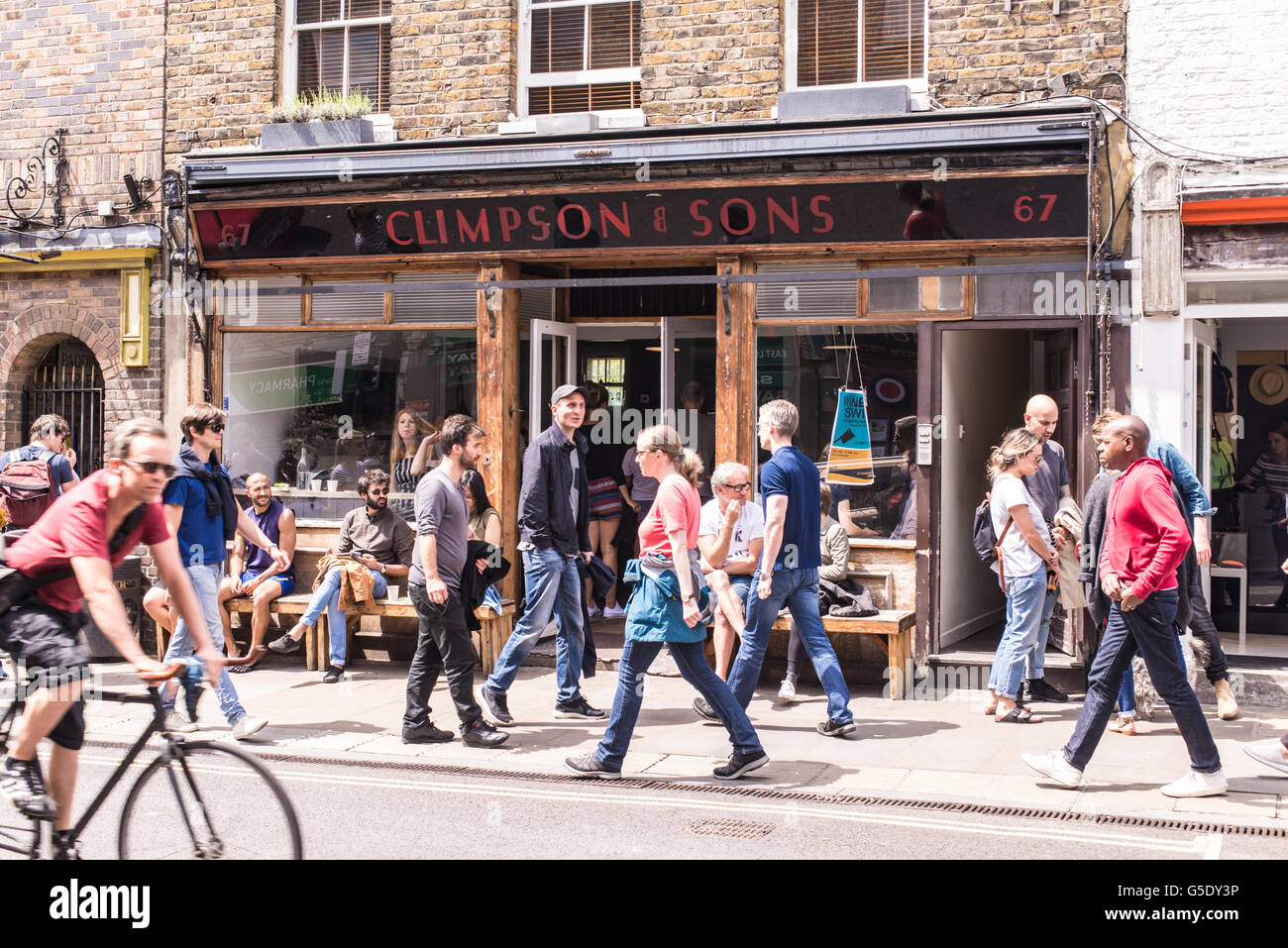 La gente seduta al di fuori di un café gustando una birra al sole nel mercato di Broadway, la zona est di Londra Foto Stock