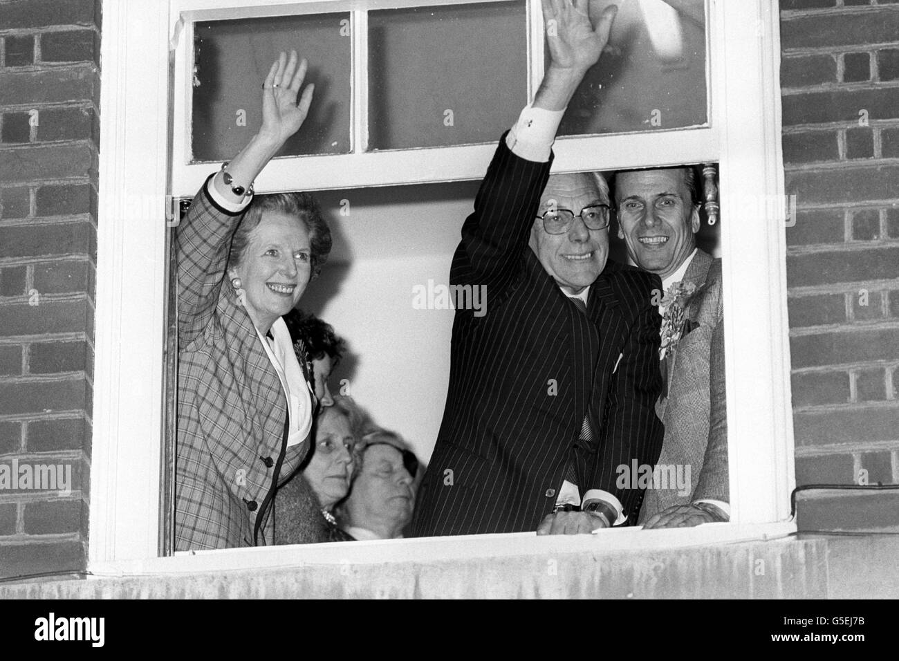 Giubilo del primo ministro Margaret Thatcher, sostenuto dal marito Denis e dal presidente del partito Tory Norman Tebbit, mentre lei ondeggia dalla finestra del Conservatory Party Central Office di Londra quando è stato confermato che lei era scosso alla vittoria. Foto Stock