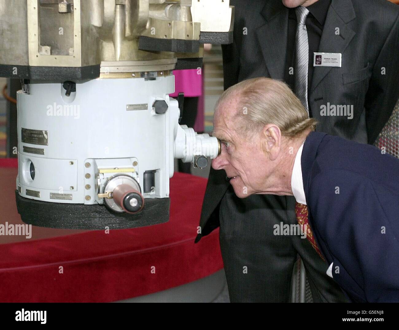 Il Duca di Edimburgo guarda attraverso un periscopio, guardato da George Bennett, Presidente del Centro della Scienza, durante la visita del Duca e della Regina Elisabetta II al Museo della Scienza di Glasgow, Scozia. Foto Stock