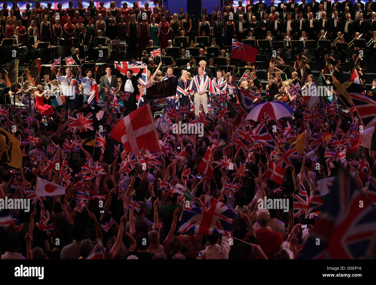 Il pubblico ondeggia bandiere mentre gli atleti vincitori di medaglia del Team GB si uniscono al palco della Royal Albert Hall, durante il finale della BBC Last Night of the Proms 2012. Foto Stock