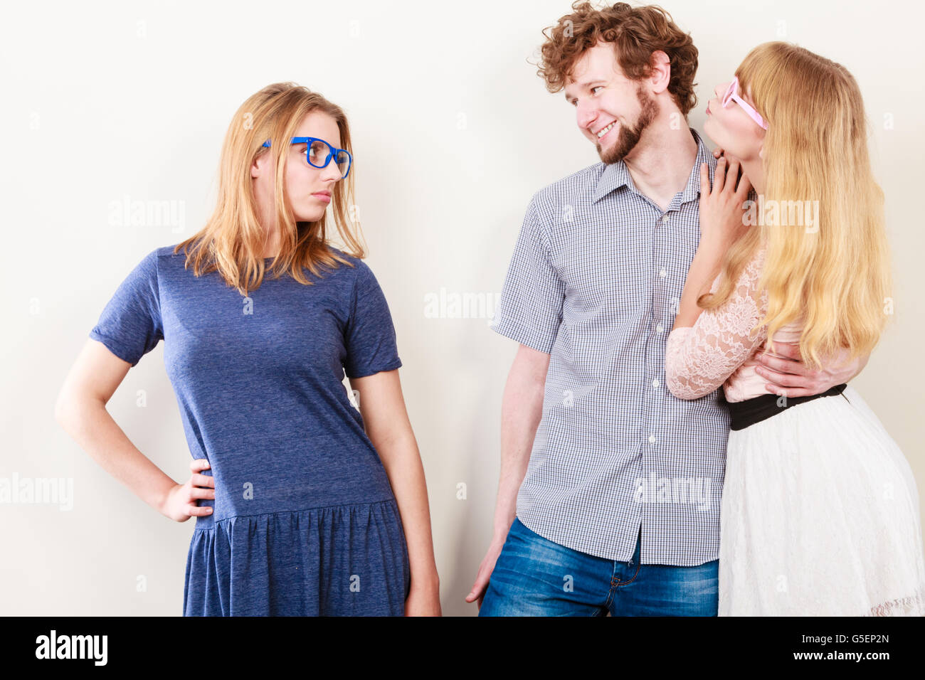 La gelosia e il tradimento del concetto. Abbandonata la ragazza jelous guardando sulla coppia felice - giovani attraenti blondie donna baciare bello Foto Stock